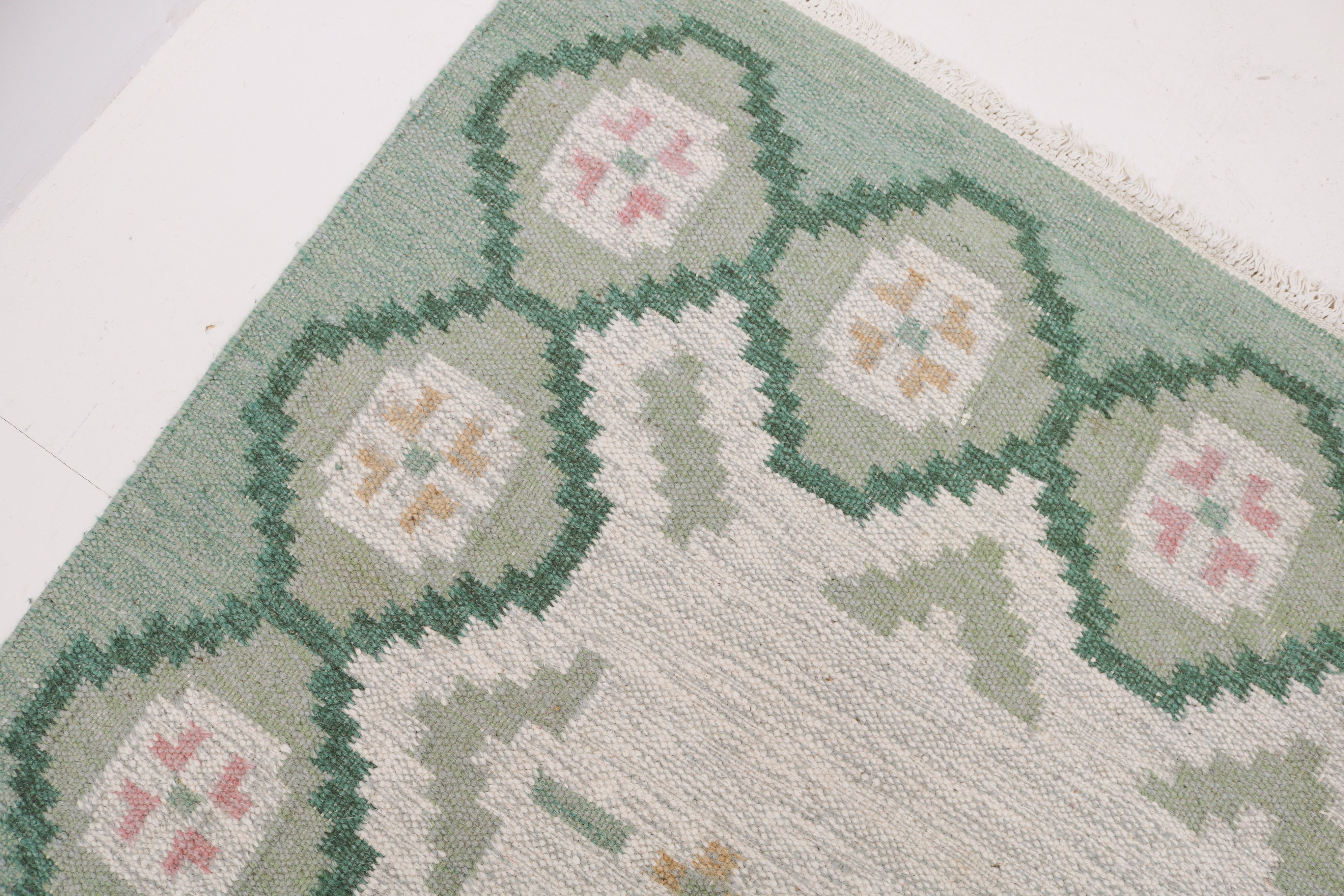 Close-up of green ivory and grey geometric pattern on vintage Swedish wool Kilim rug