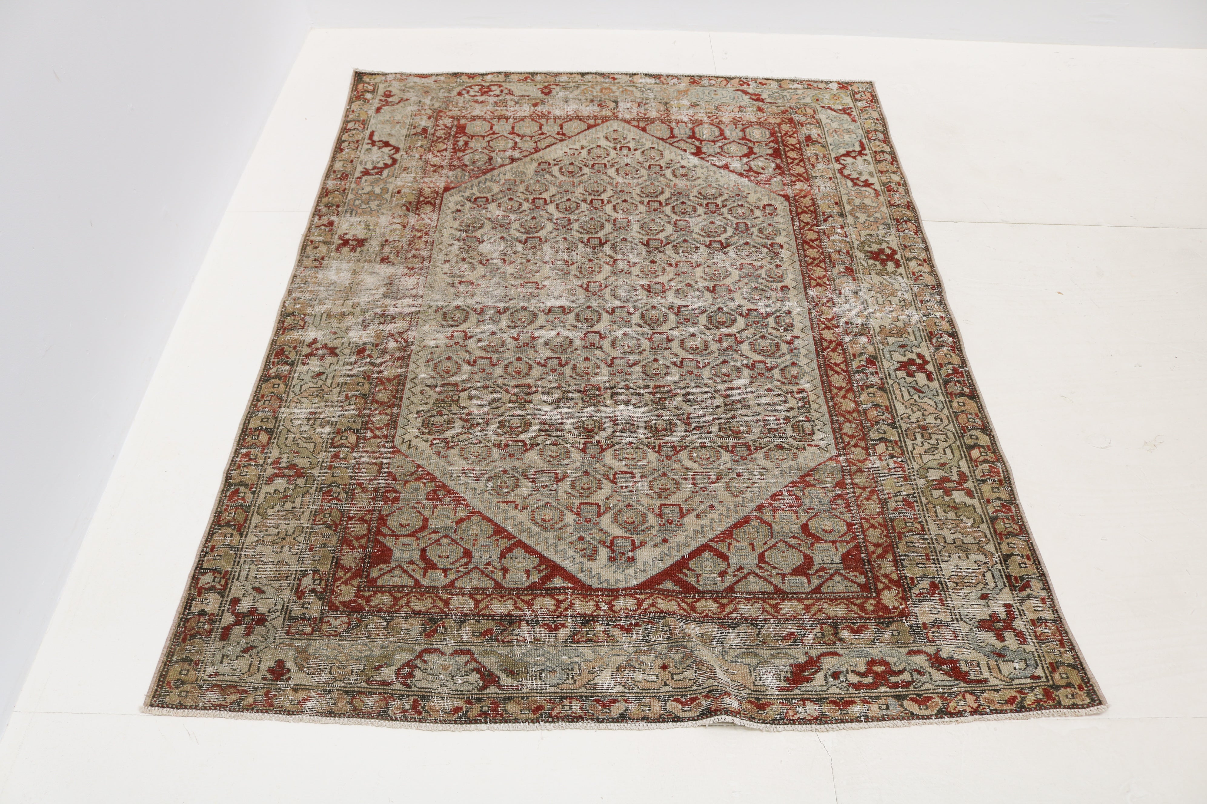 Close-up of antique Persian Malayer rug showing naturally worn wool pile and faded geometric motifs