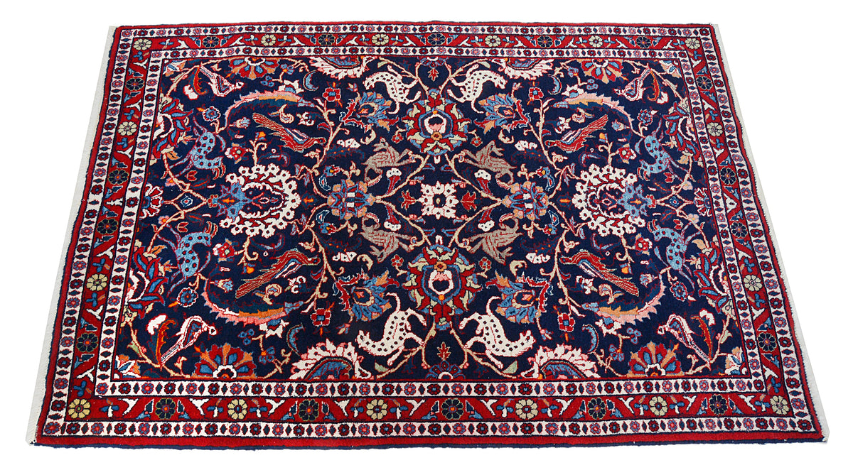 Full Persian Mashhad rug showing all-over floral pattern in navy, red and ivory