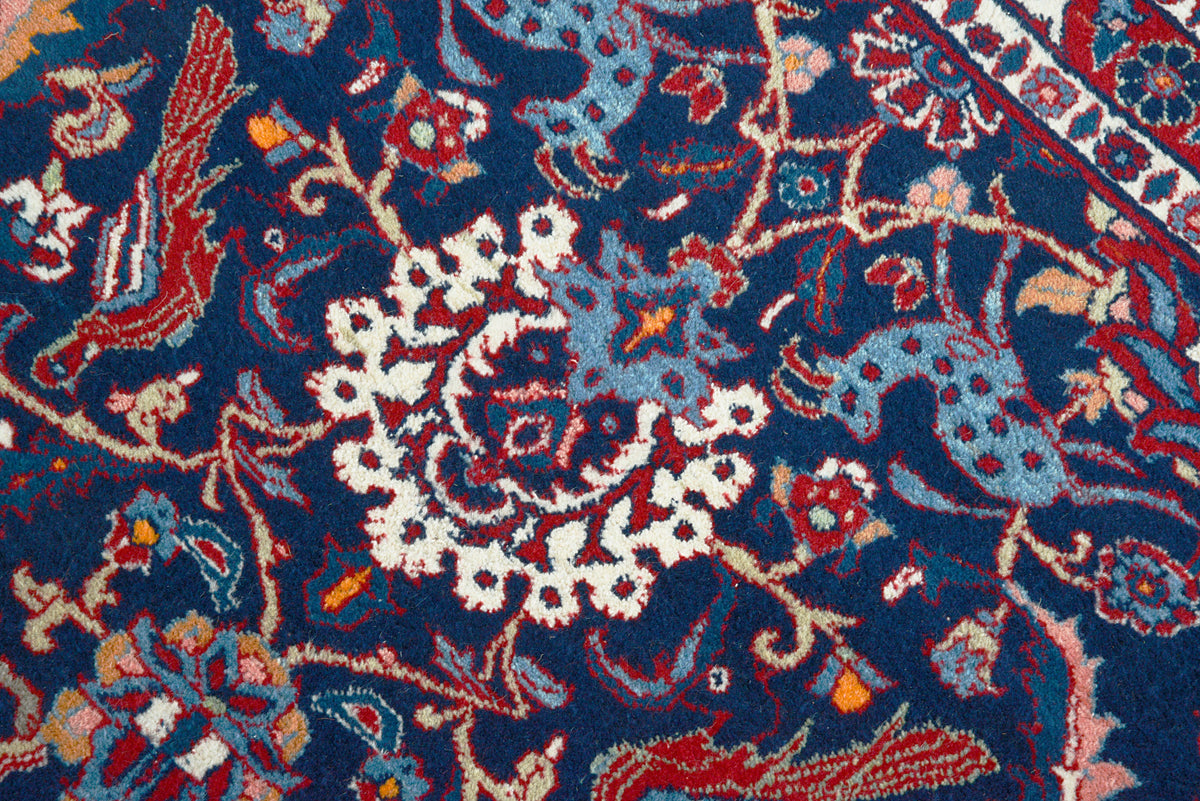 Close-up of vintage Mashhad rug with intricate floral motifs and decorative border