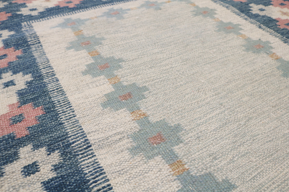 Close-up of Kilim rug with geometric flowers in ivory, pink and pale blue