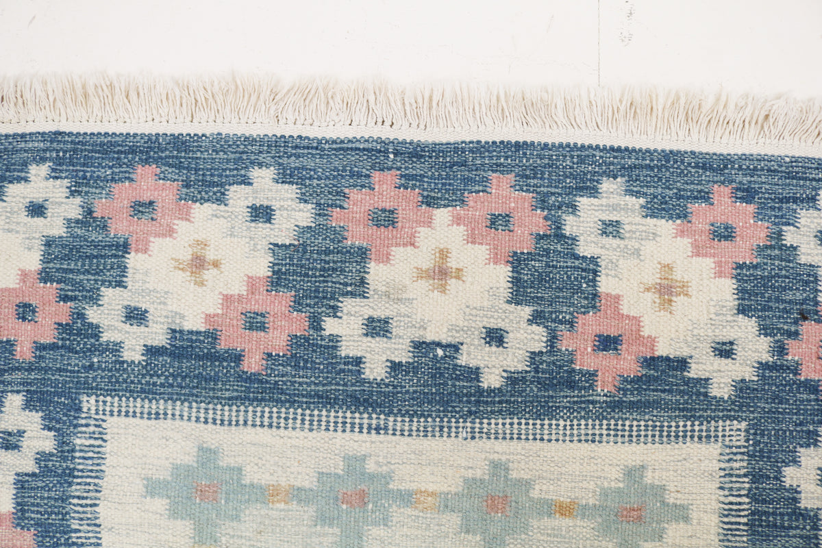 Close-up of vintage Kilim rug showing floral border and softly muted central field