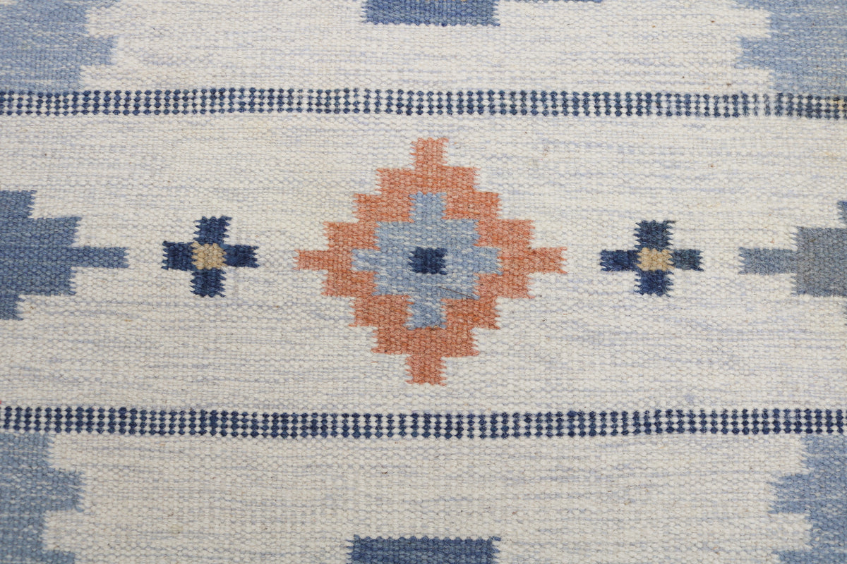 Detailed view of vintage Swedish Kilim rug with repeating geometric patterns in blue and coral