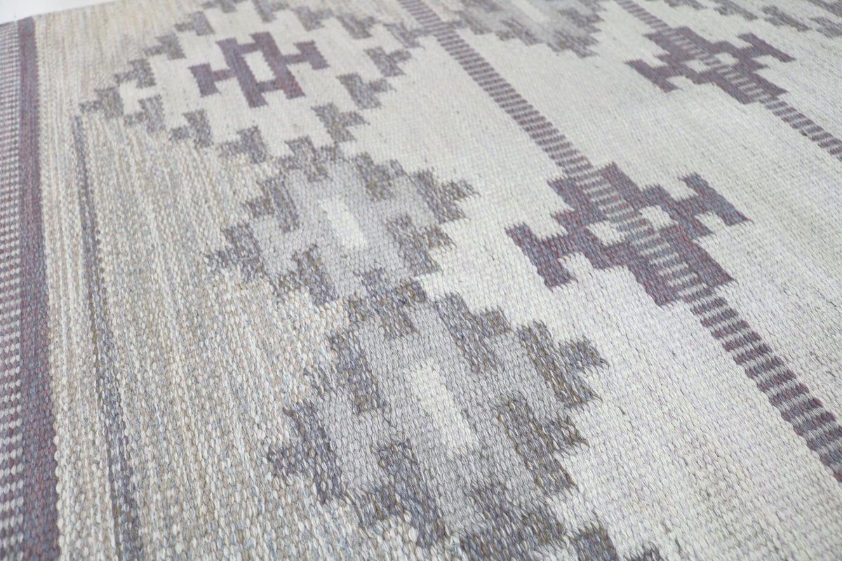 Detailed rug section with repeating geometric designs in soft grey tones
