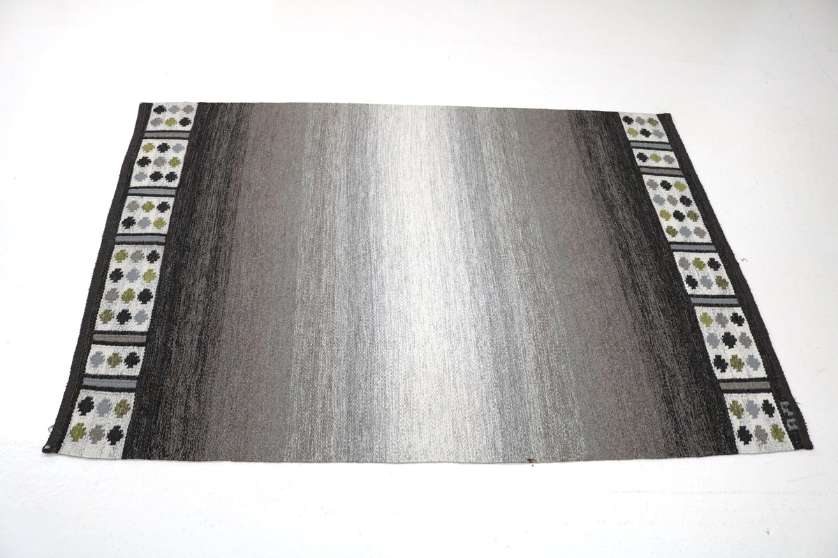 Full rug view highlighting minimalist grey field and contrasting floral border