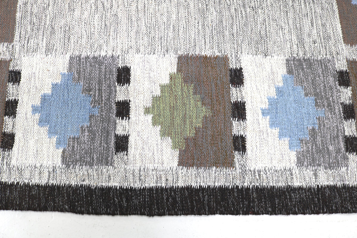 Detailed Swedish Kilim rug surface featuring repeating geometric blocks in muted Scandinavian colours