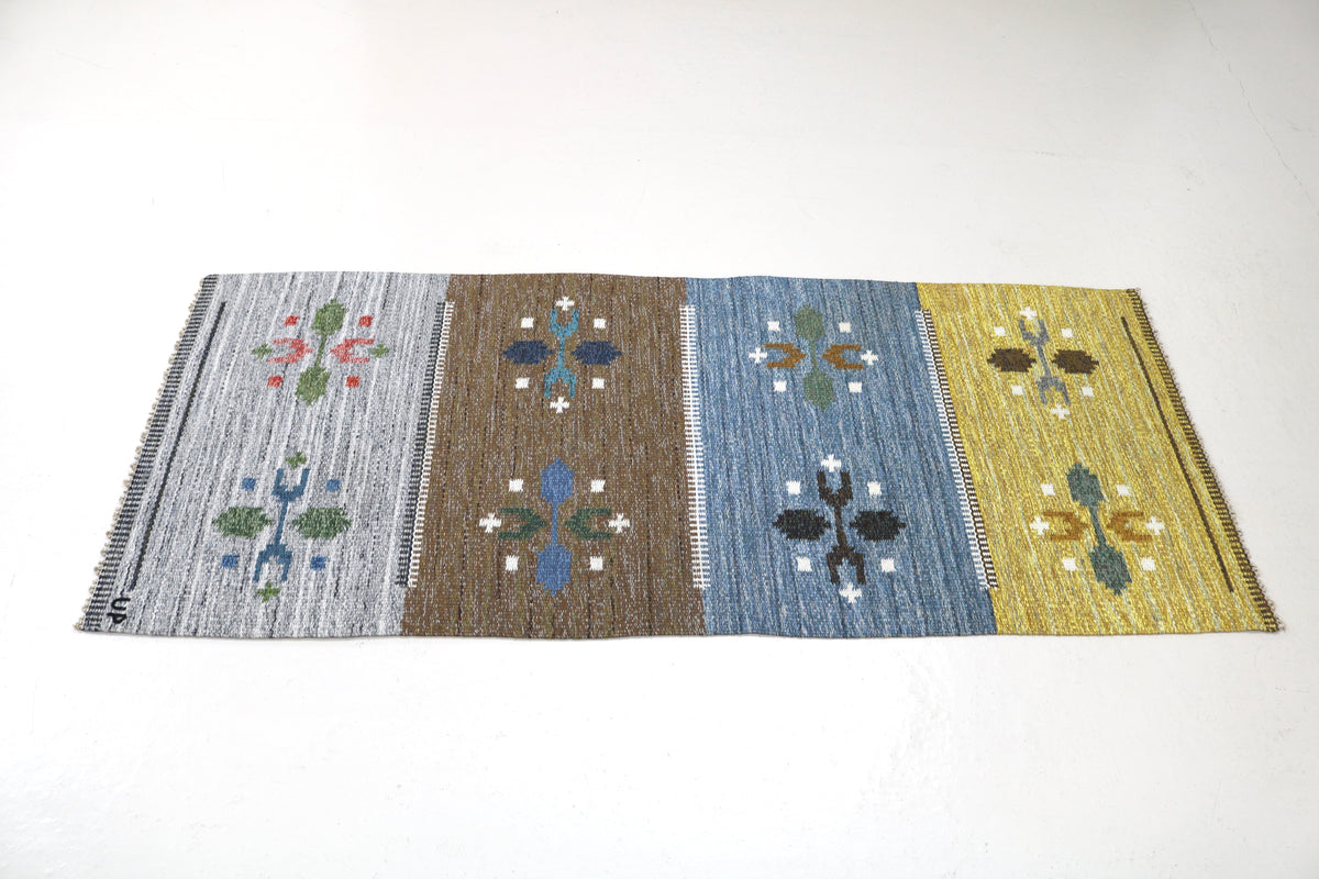 Angled view of Swedish Kilim rug featuring blue, brown, grey and yellow colour blocks