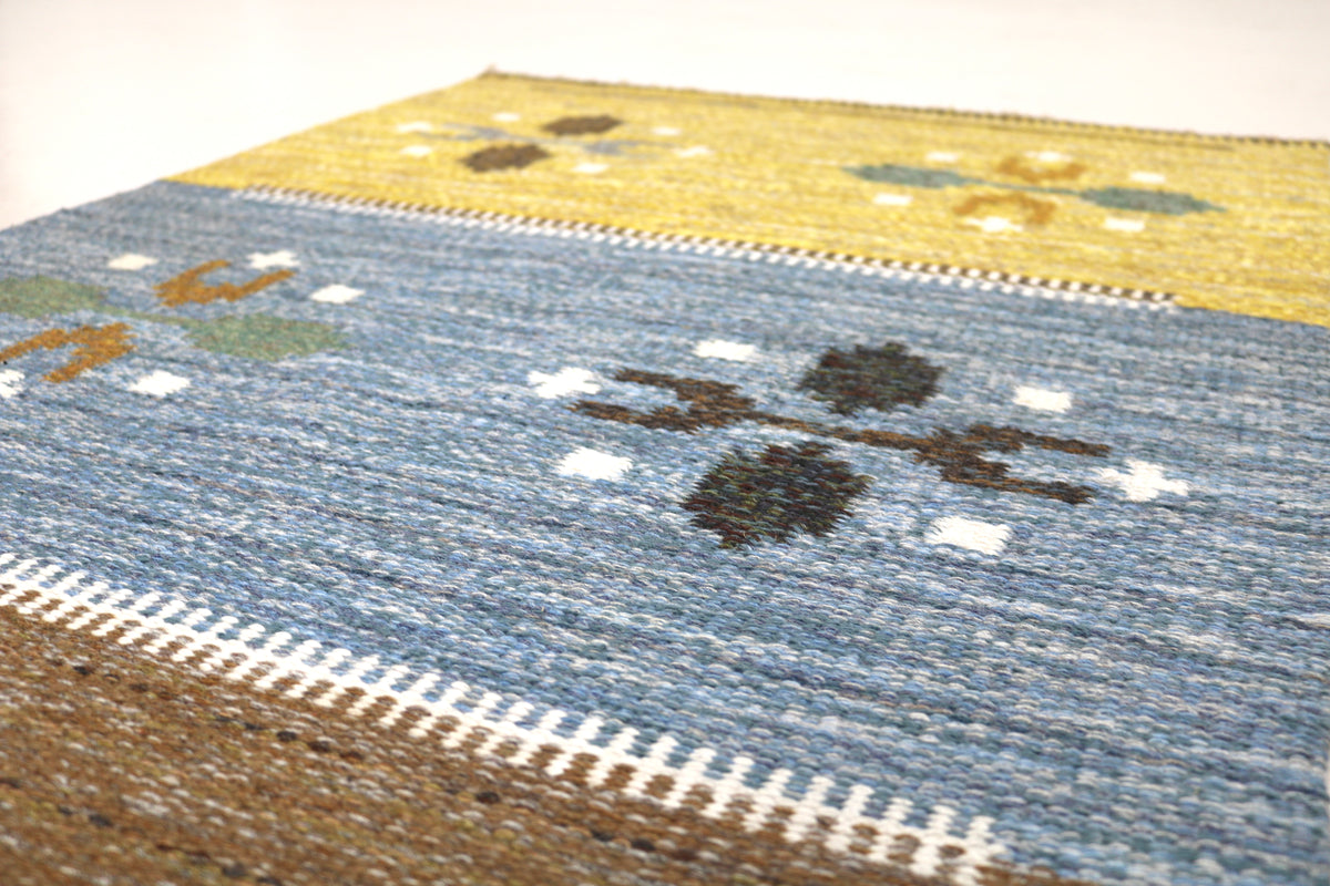 Detailed Swedish Kilim rug showing blue and brown bands with small geometric motifs