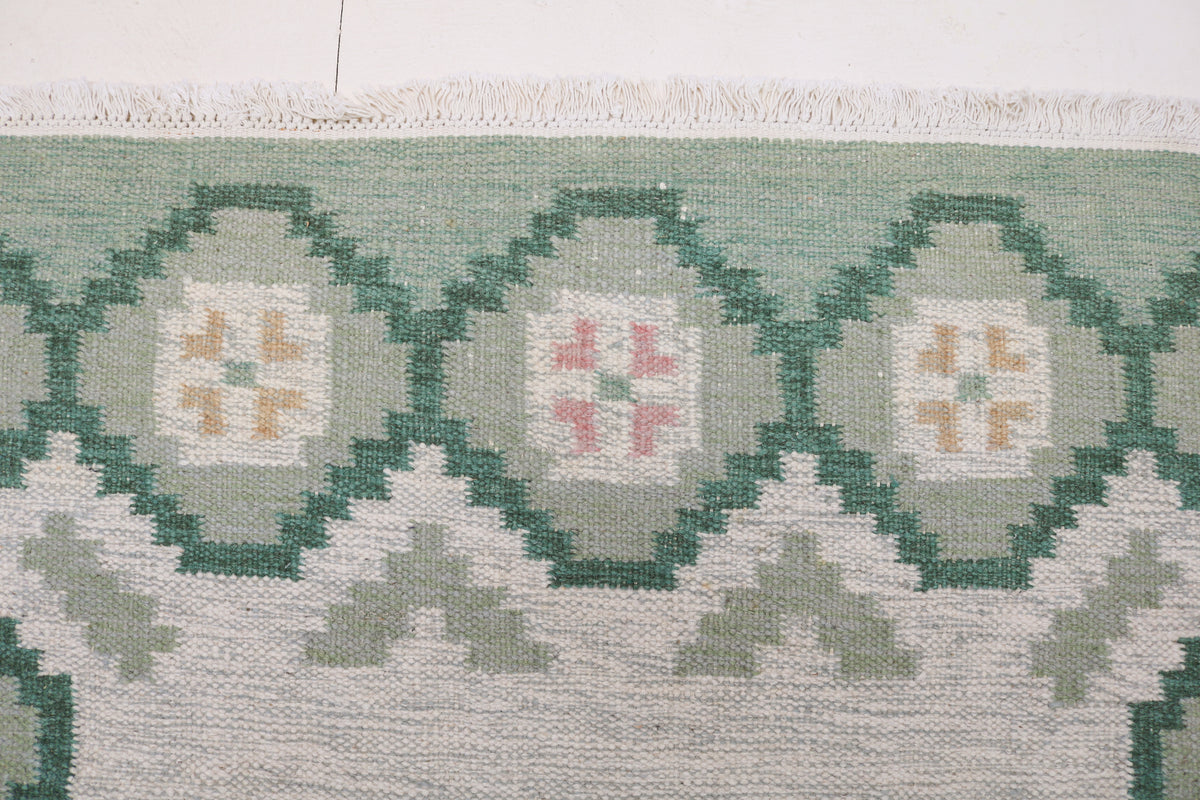 Detailed Swedish Kilim rug showing repeating floral medallions and muted Scandinavian colours