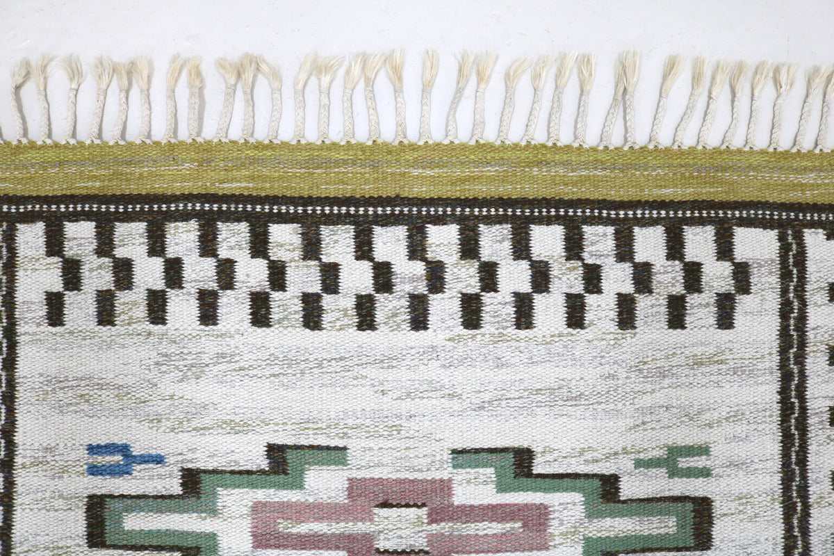 Detailed Swedish Kilim rug border featuring repeating geometric patterns and fringed edge
