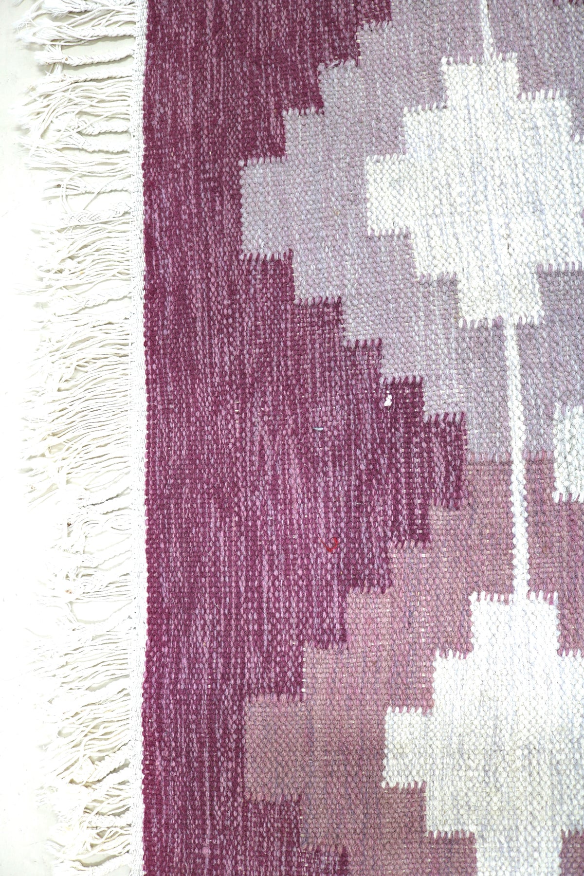 Close-up of vintage Swedish Kilim rug showing geometric motifs beside the ivory field
