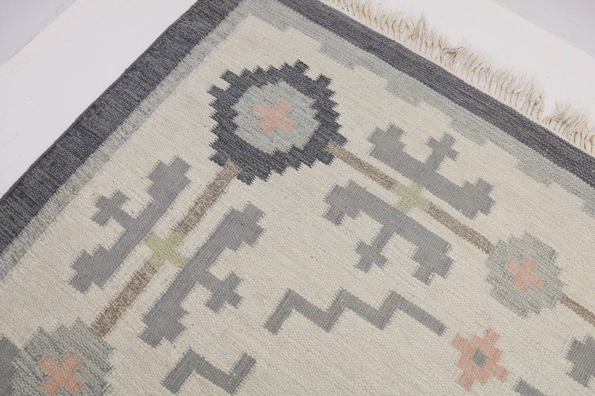 Close-up of Kilim rug corner with charcoal border and geometric floral motifs