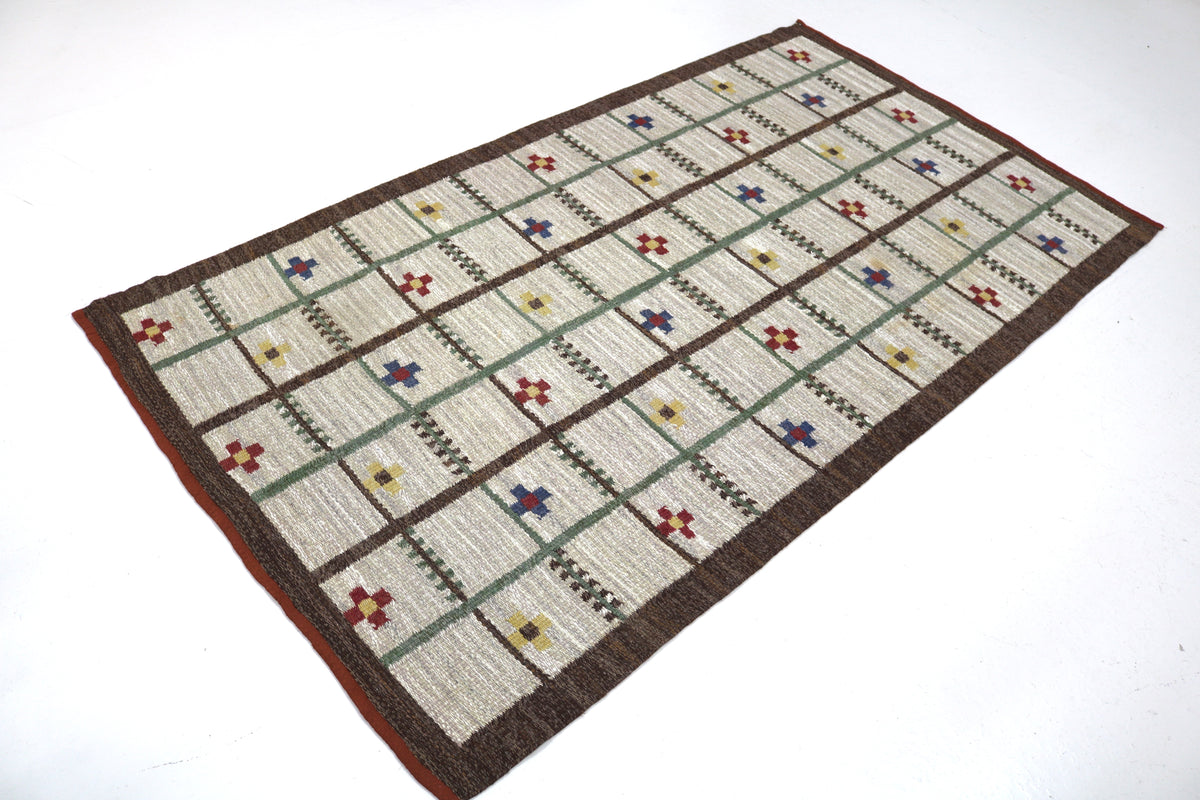 Full view of vintage Swedish Kilim rug with structured grid design and dark border
