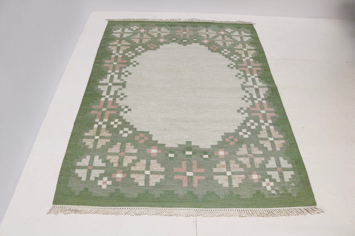 Full view of vintage Swedish Kilim rug with spacious pale grey field and decorative border