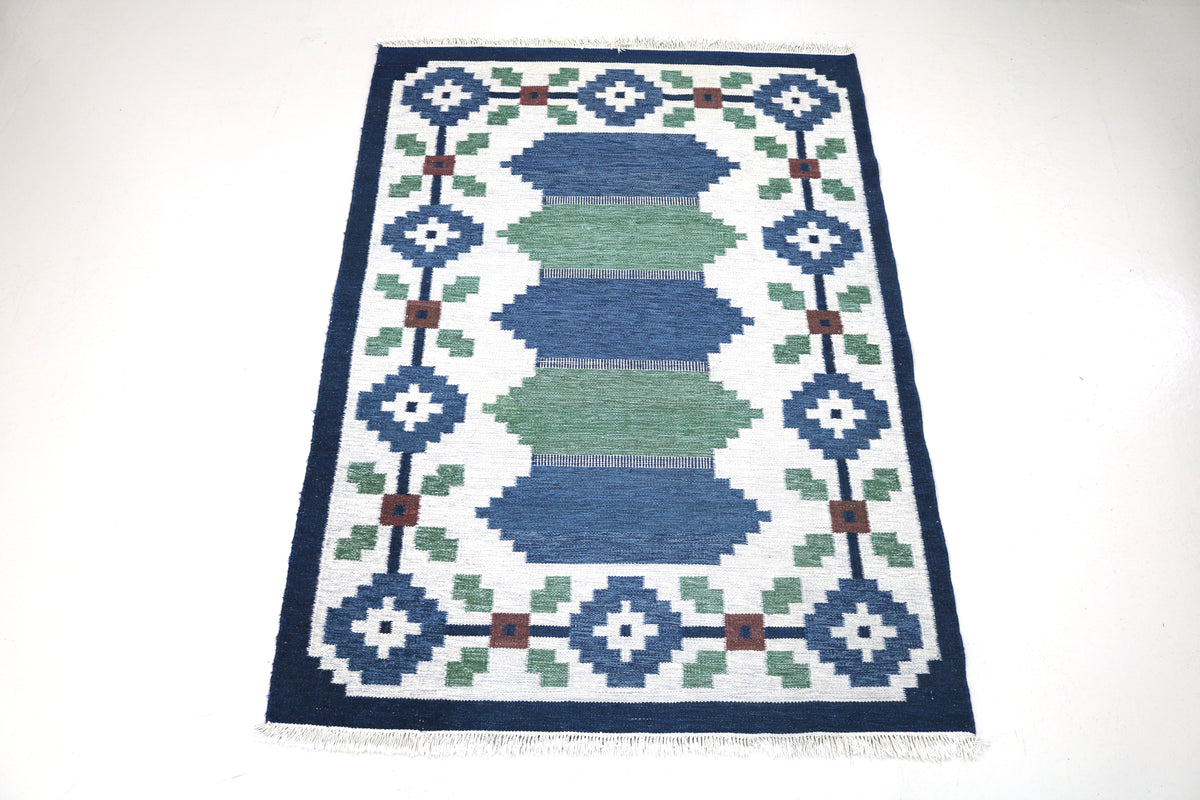 Full view of vintage Swedish Kilim rug with repeating geometric design in blue, green and ivory