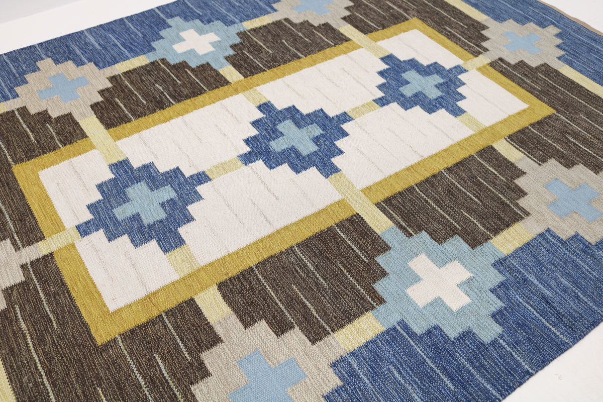 Close-up of Swedish Kilim rug showing repeating blue and ivory geometric motifs with yellow accents
