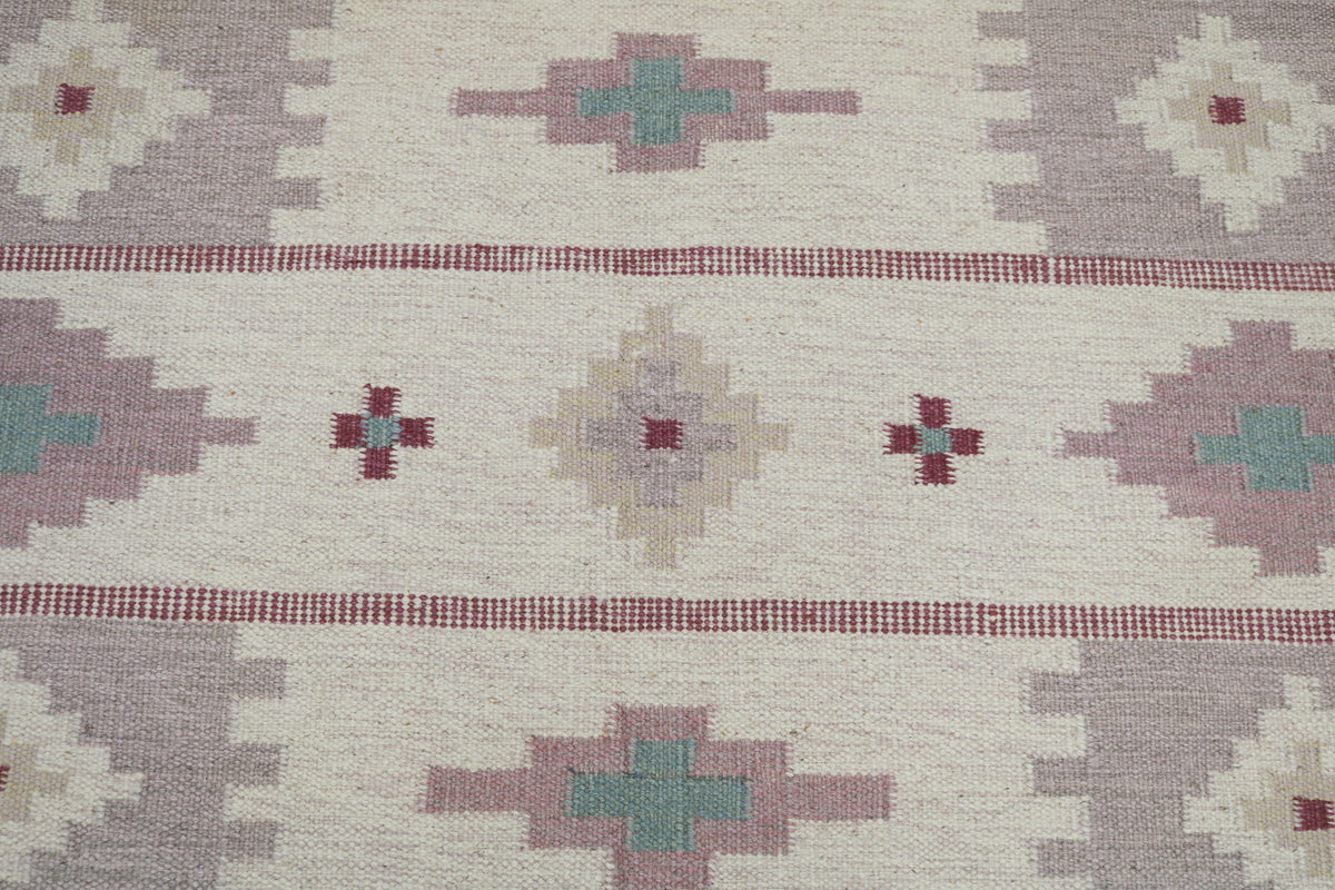 Detailed Swedish Kilim rug surface featuring repeating geometric bands and muted Scandinavian colours