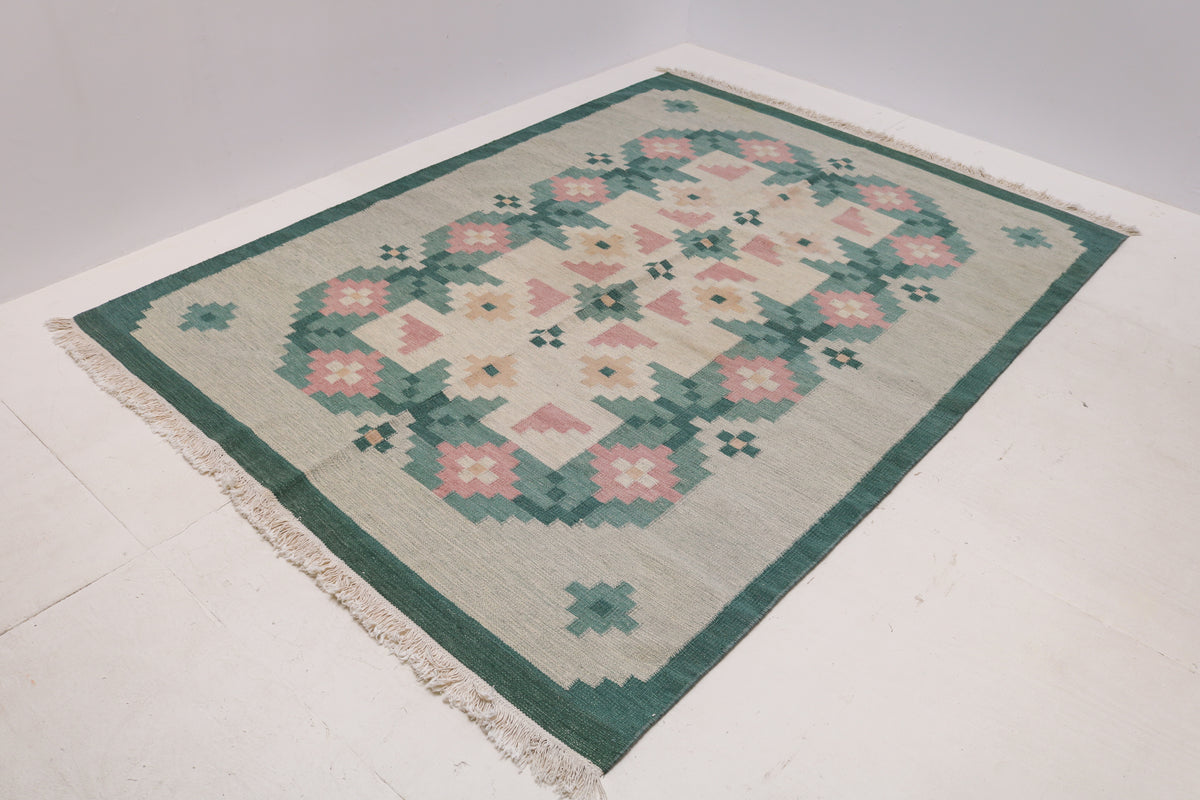 Vintage Swedish Kilim rug showcasing geometric floral patterns across a broad pale field