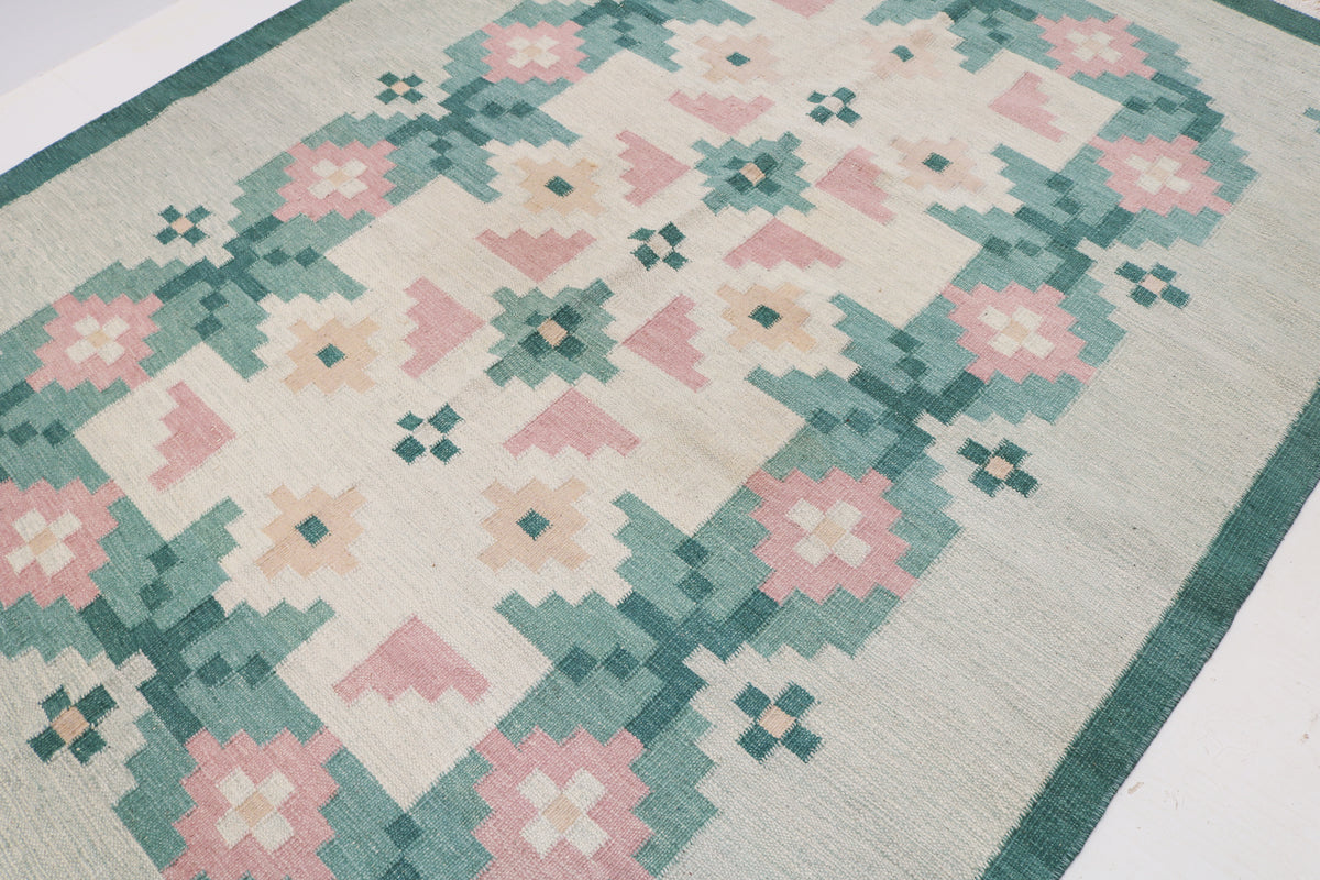 Close-up of Kilim rug with large geometric flowers in dusty pink, ivory and teal