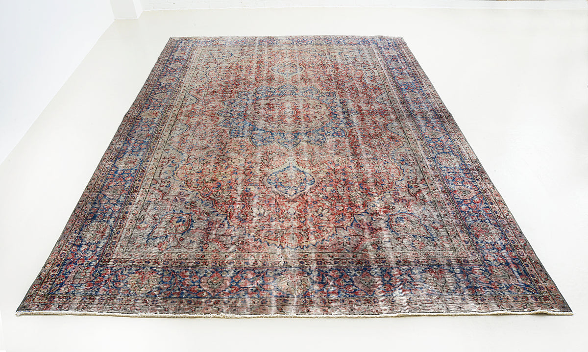 Full view of vintage Turkish carpet with softly faded central medallion and detailed borders