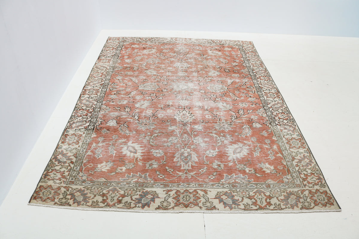 Antique Persian rug with faded coral tones and traditional floral motifs