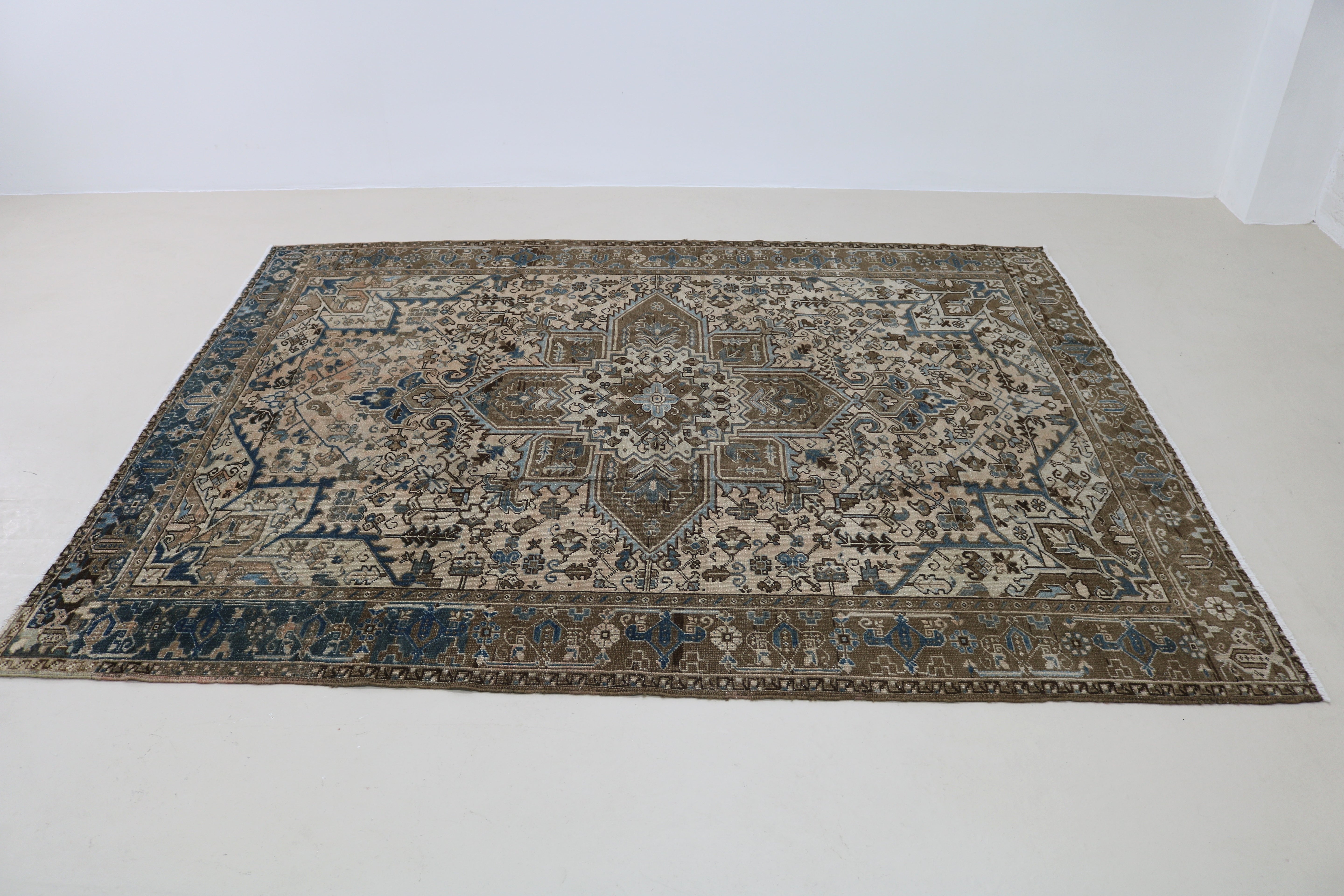 Perspective view of decorative antique Heriz carpet laid on floor
