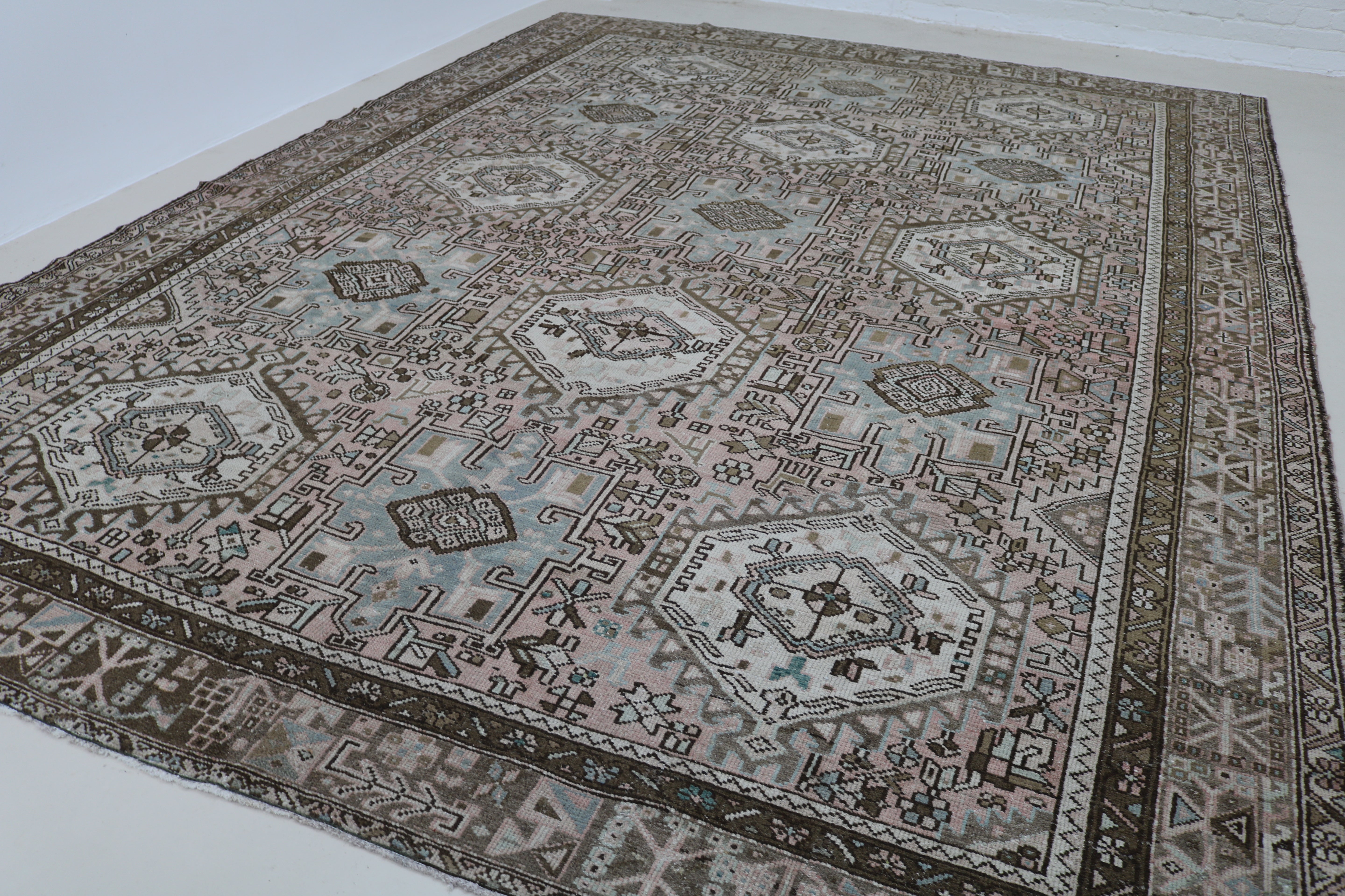 Angled view of antique Persian Heriz–Karaja carpet showing field and borders
