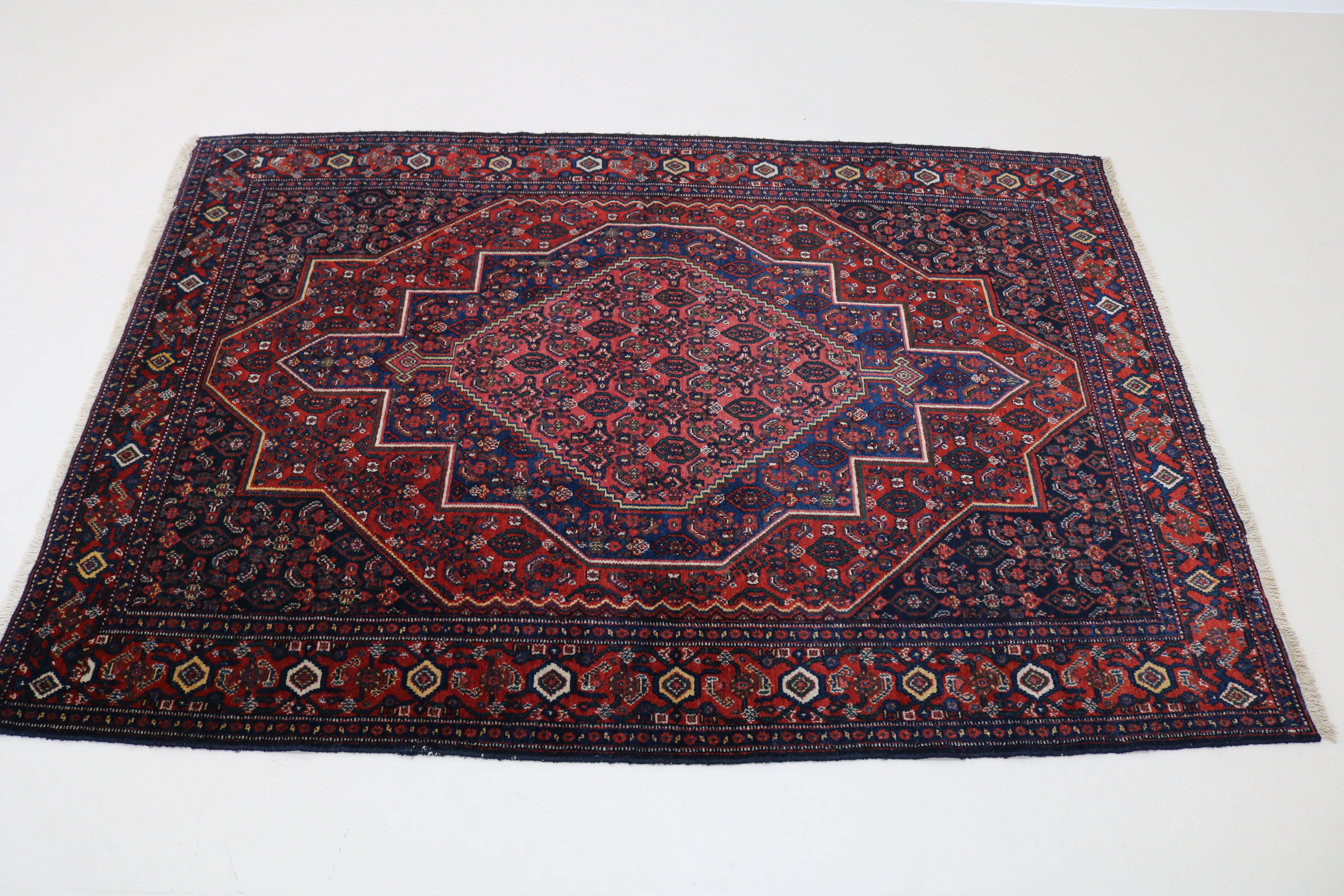 Perspective view of antique Persian Senneh rug on floor
