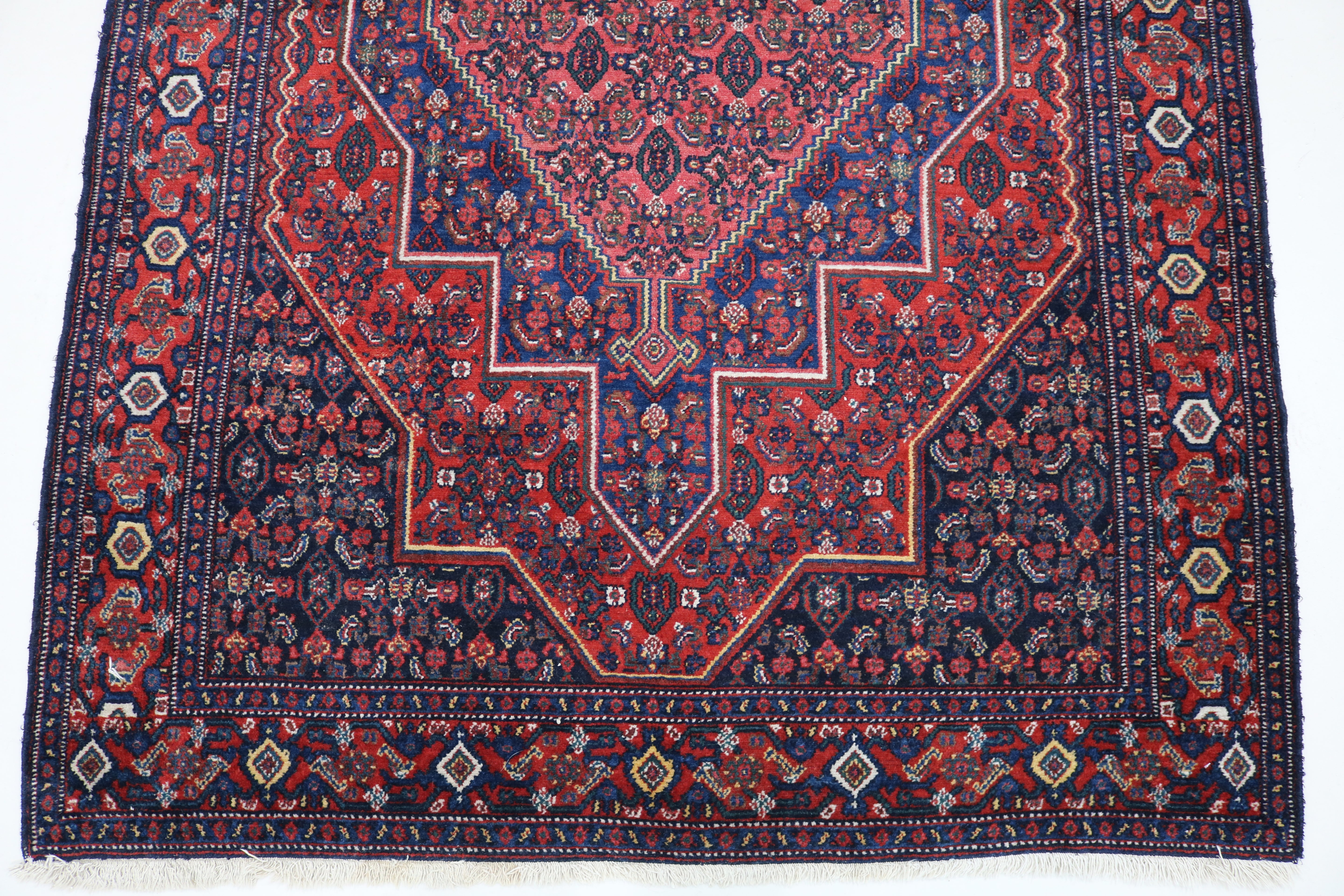 Close-up of hand-knotted wool texture on antique Persian Senneh rug
