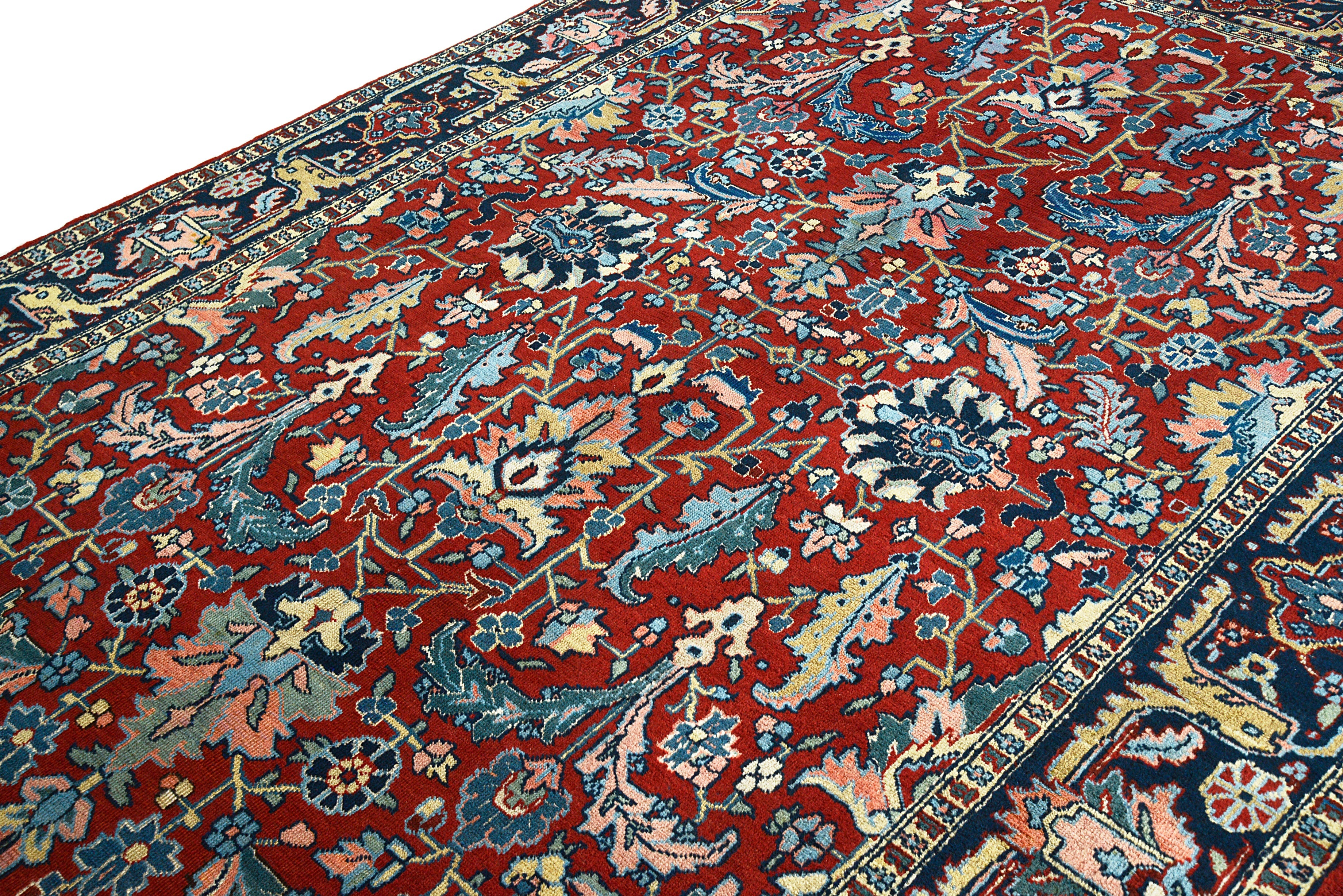 Large antique Persian Heriz carpet featuring bold pattern and deep blue border
