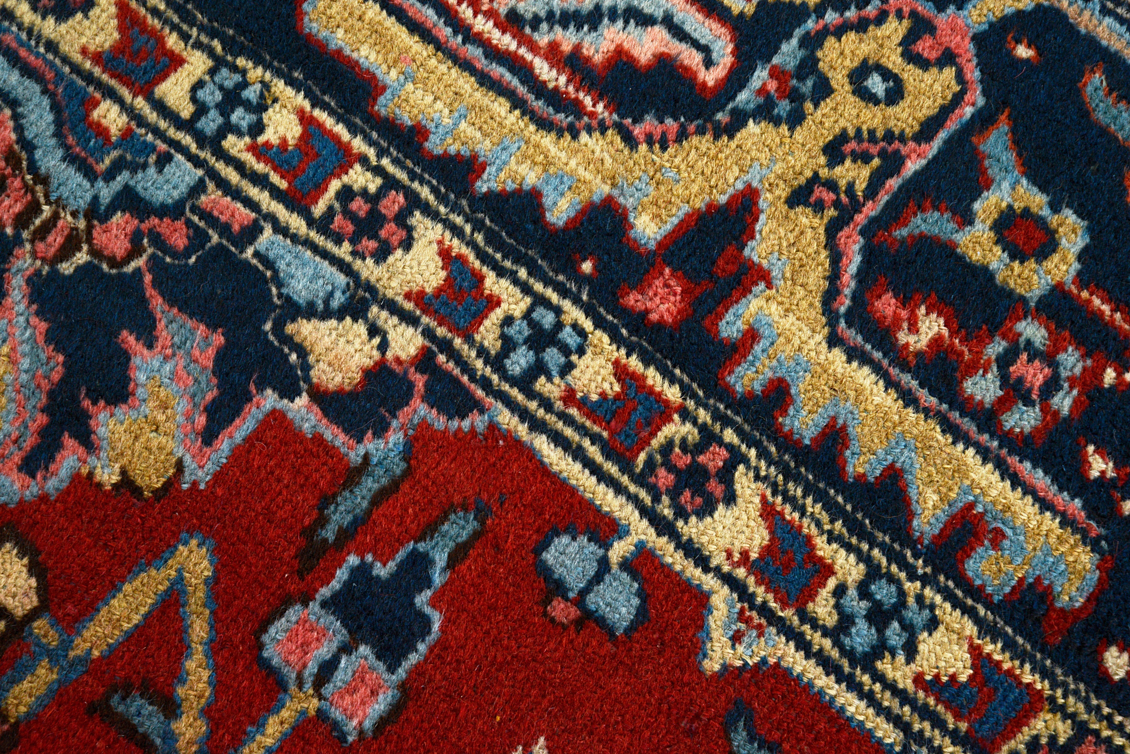 Close-up details of antique Persian Heriz carpet showing wool texture, motifs, and natural patina
