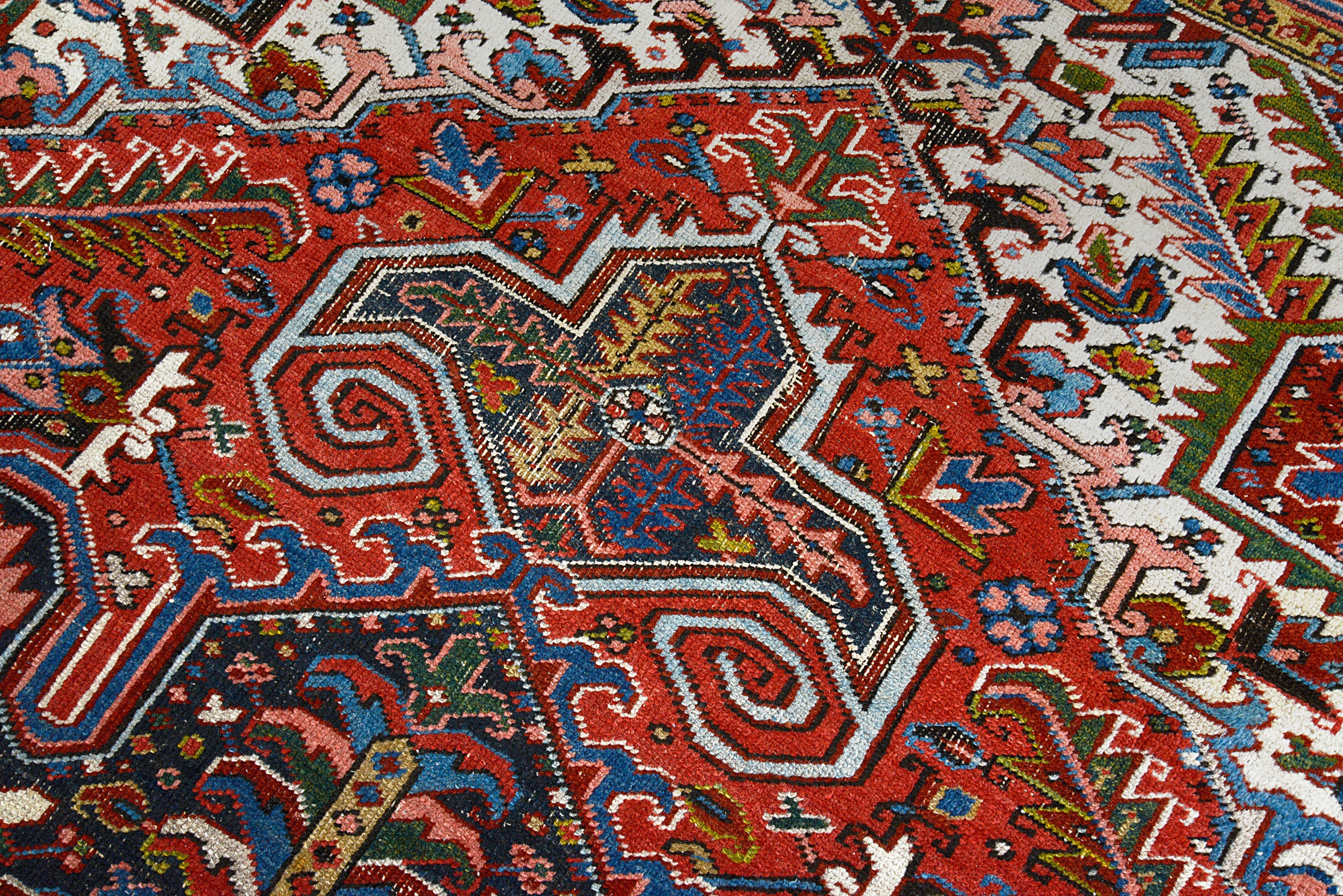 Close-up details of antique Persian Heriz carpet showing wool texture, motifs, and aged patina
