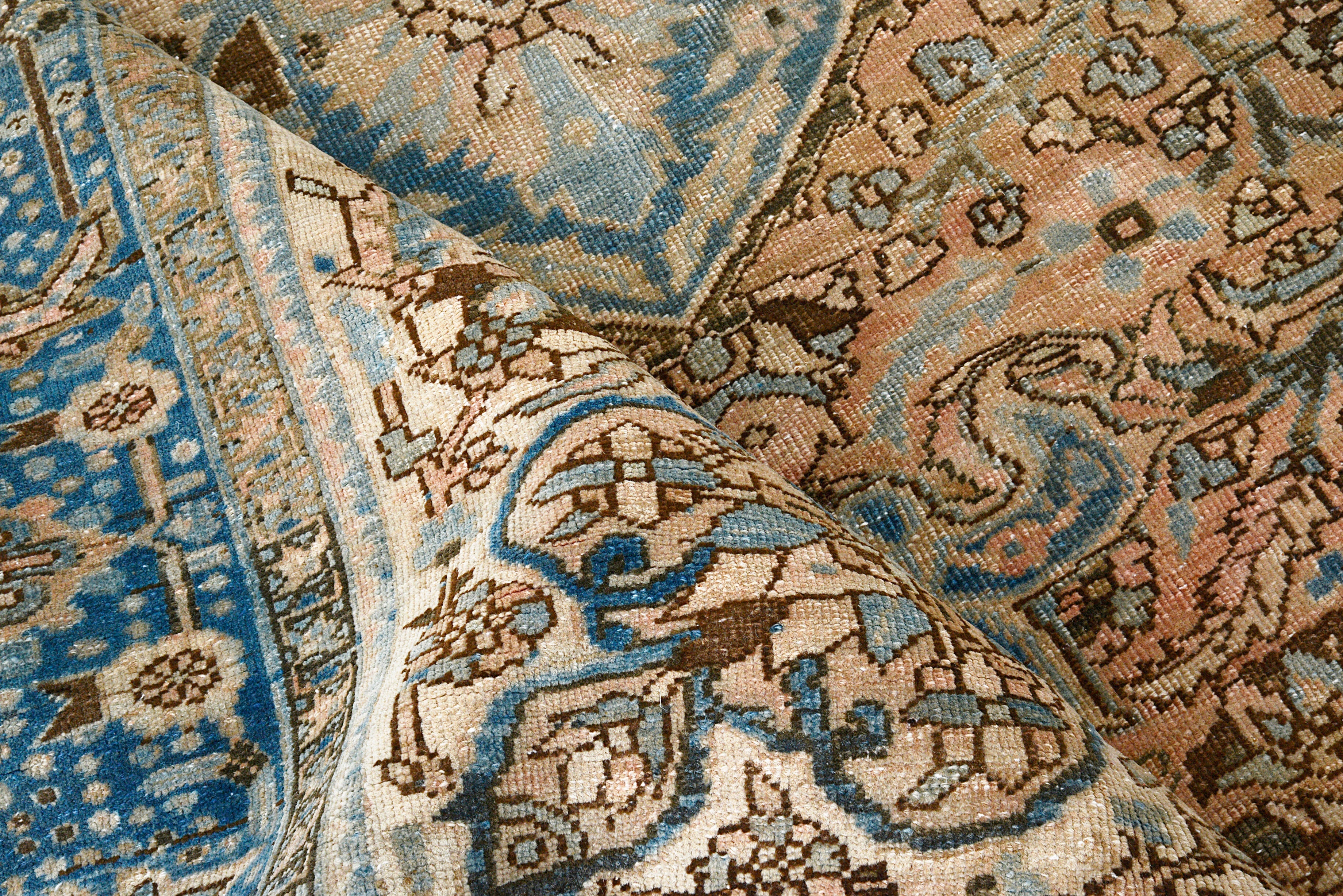 Close-up details of vintage Persian Heriz carpet showing wool texture, motifs, and natural patina
