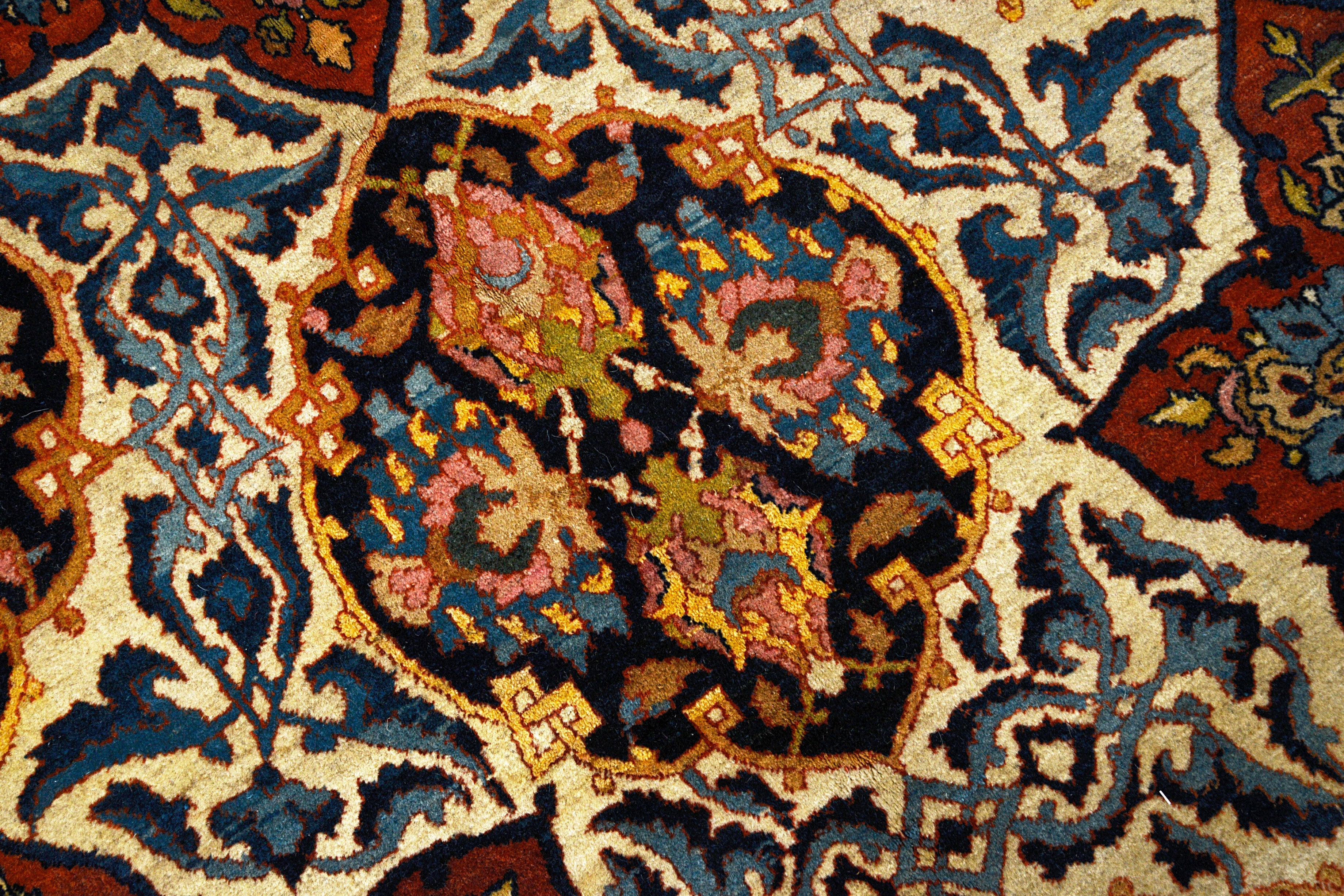 Close-up details of fine antique Isfahan carpet showing wool texture, floral motifs, and aged patina
