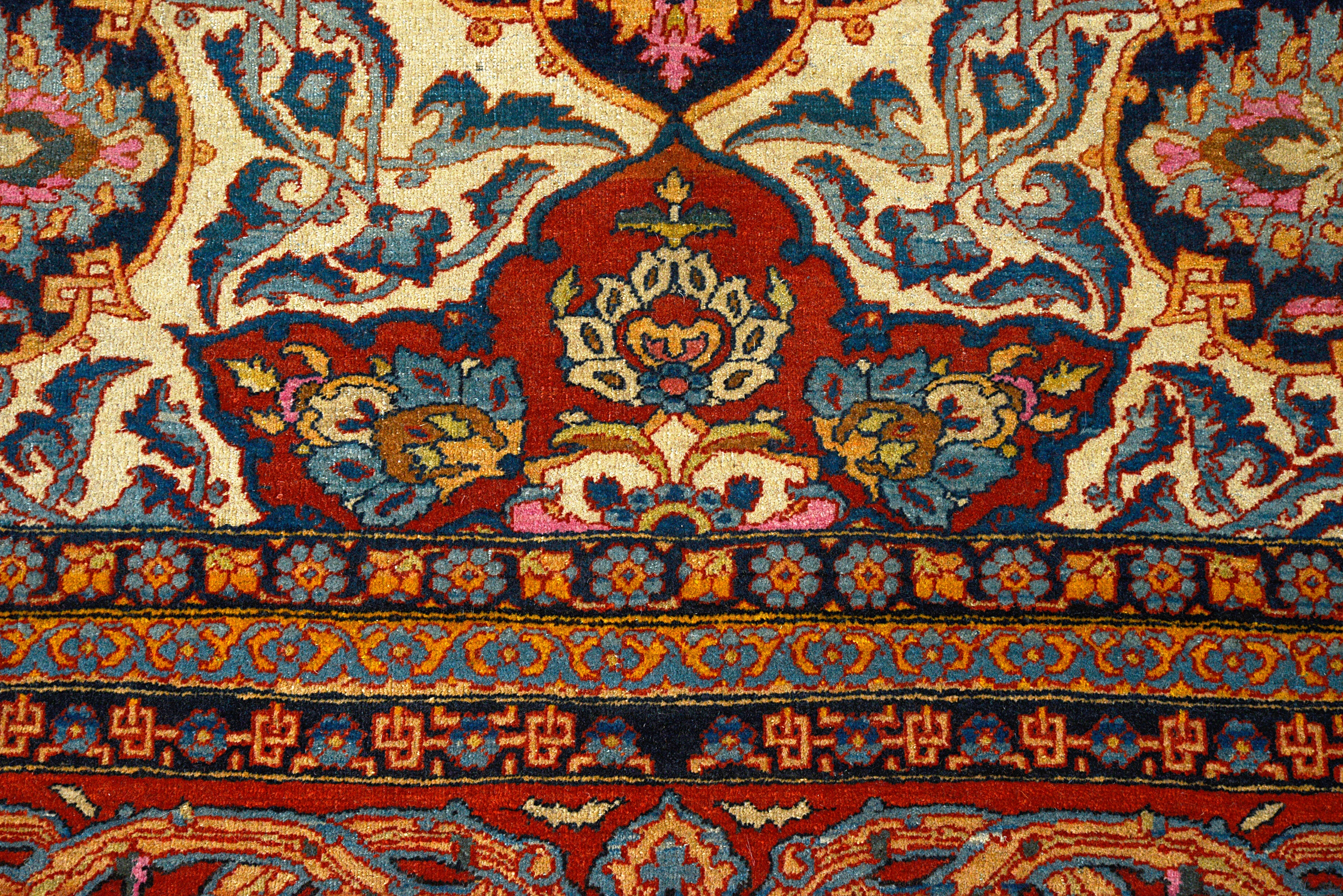 Close-up details of fine antique Isfahan carpet showing wool texture, floral motifs, and aged patina

