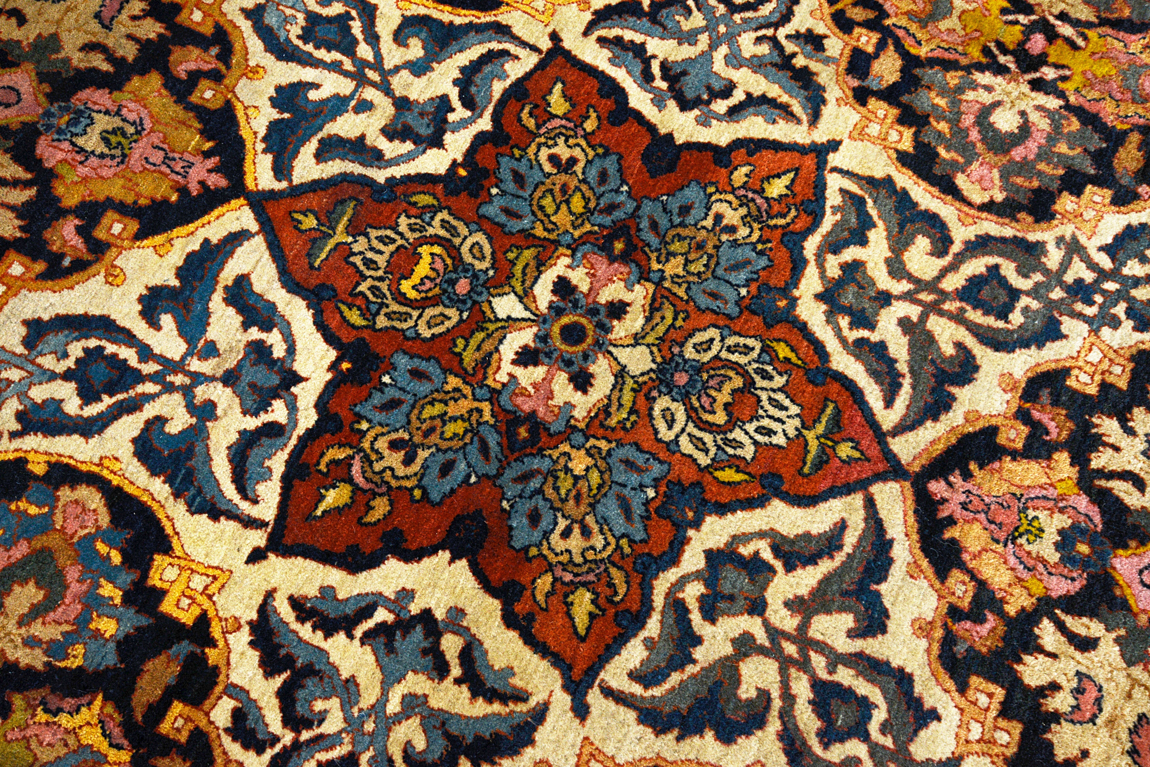 Close-up details of fine antique Isfahan carpet showing wool texture, floral motifs, and aged patina
