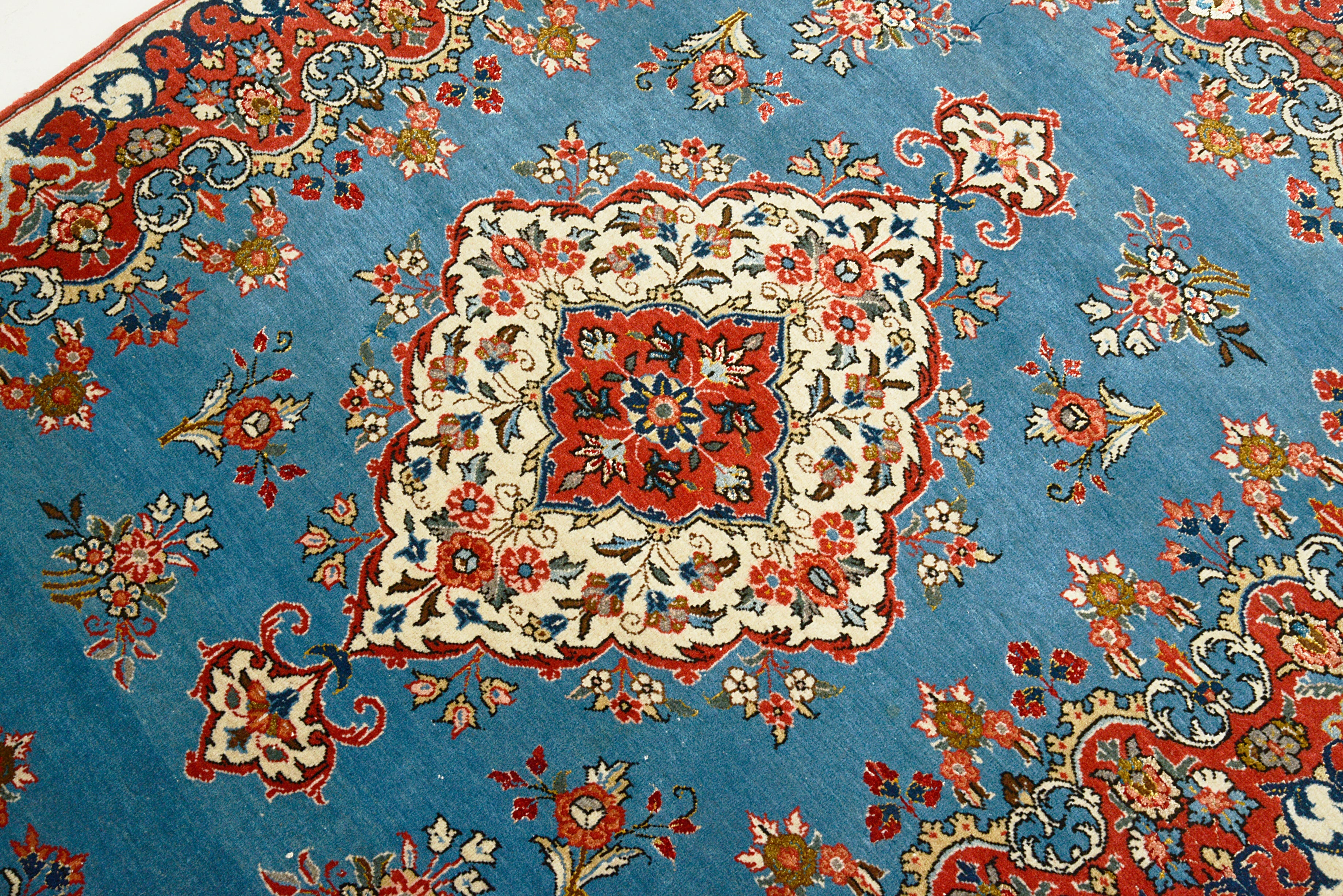Close-up details of fine antique Persian Qom rug showing wool texture, floral motifs, and aged patina
