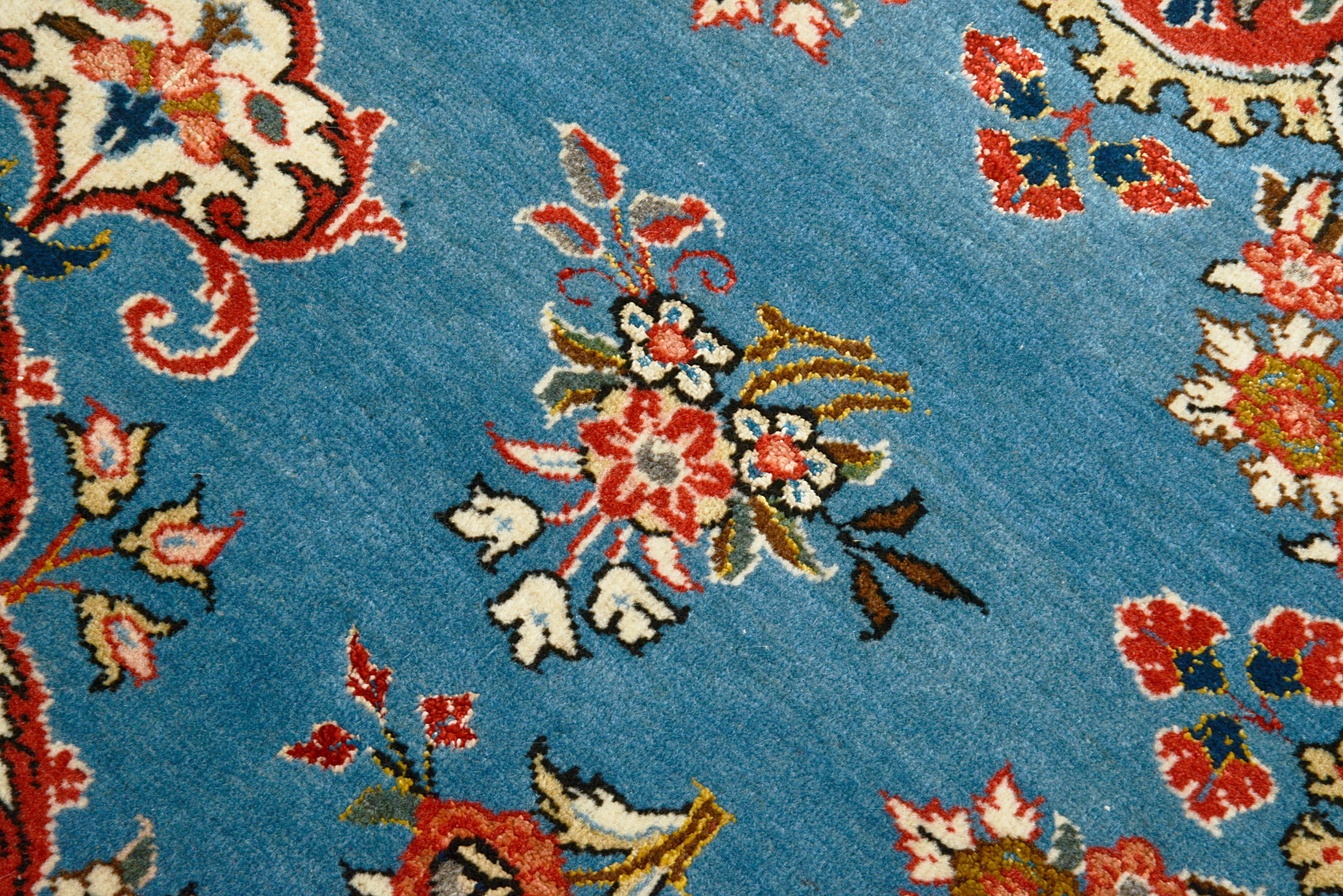 Close-up details of fine antique Persian Qom rug showing wool texture, floral motifs, and aged patina
