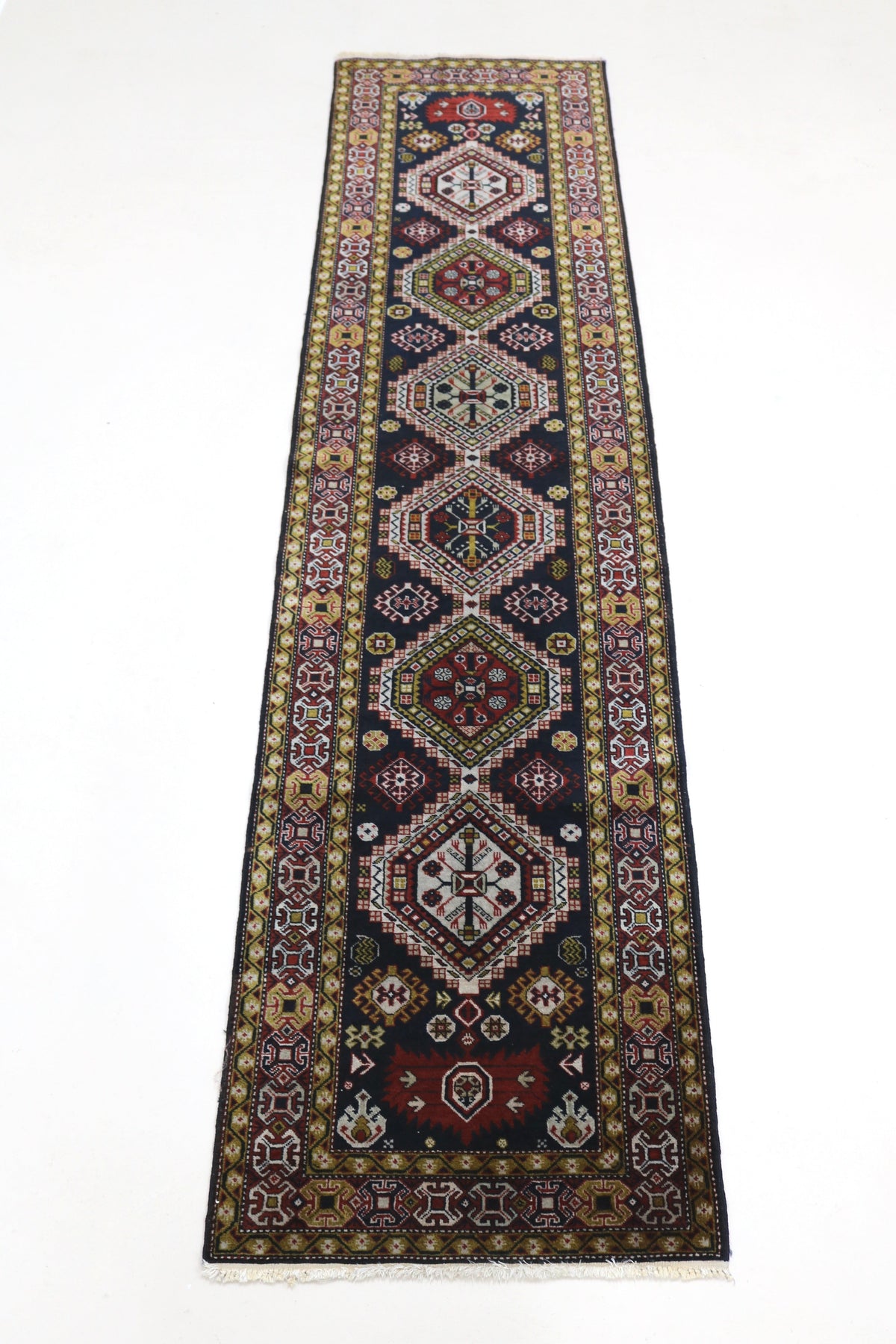 Full view of antique Irawan runner with repeating geometric medallions and narrow format