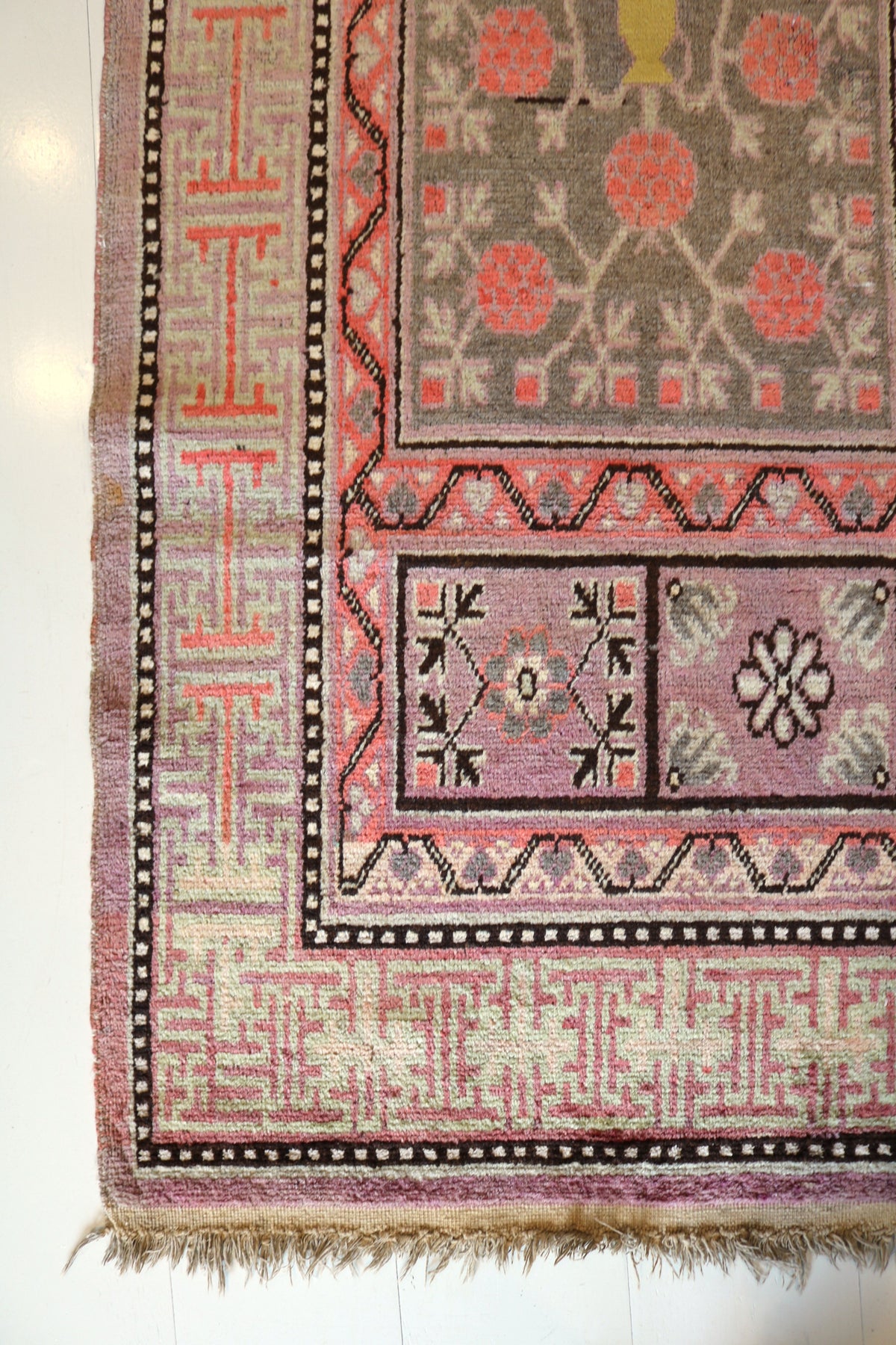 Antique Qotan rug corner with geometric floral motifs and decorative borders