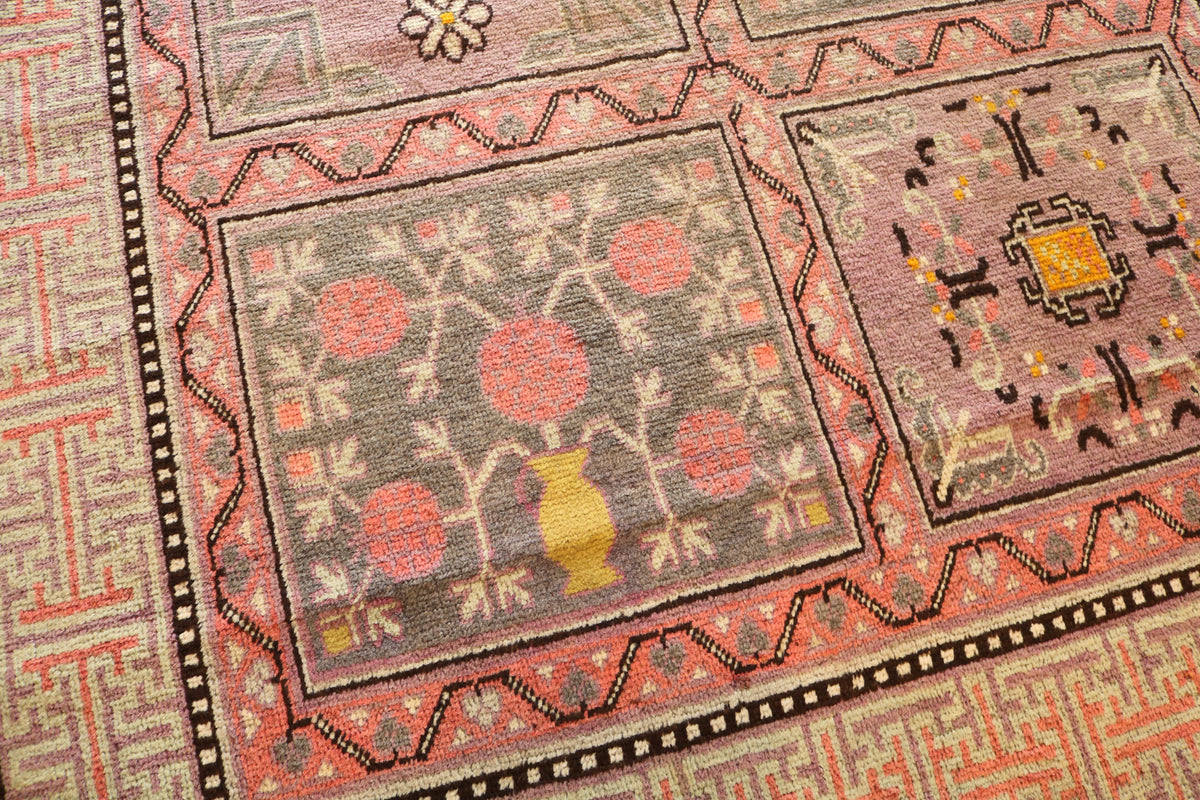 Angled Qotan rug view showing geometric panels and muted red tones
