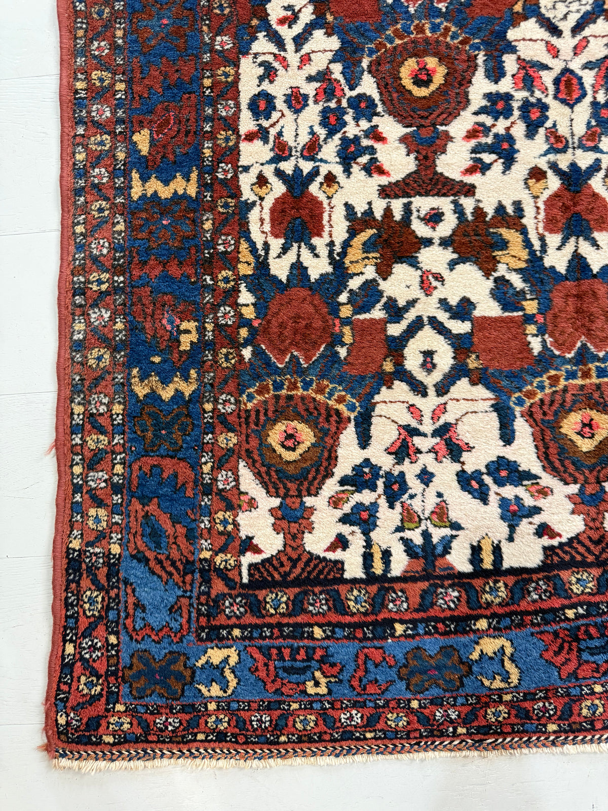 Antique Persian Afshar rug with ivory field, blue border and vibrant floral motifs