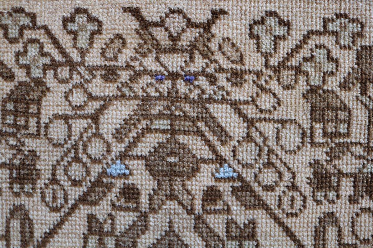 Detailed rug section featuring repeating motifs in soft neutral tones