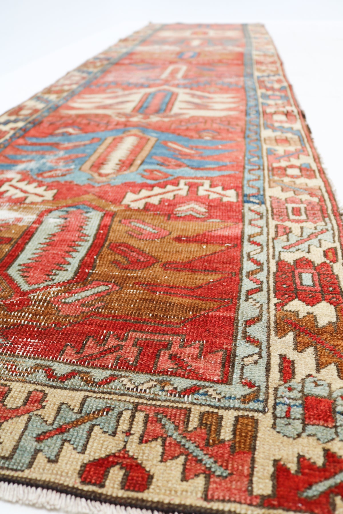 Close-up of an antique Persian runner rug showing woven texture and detailed geometric border