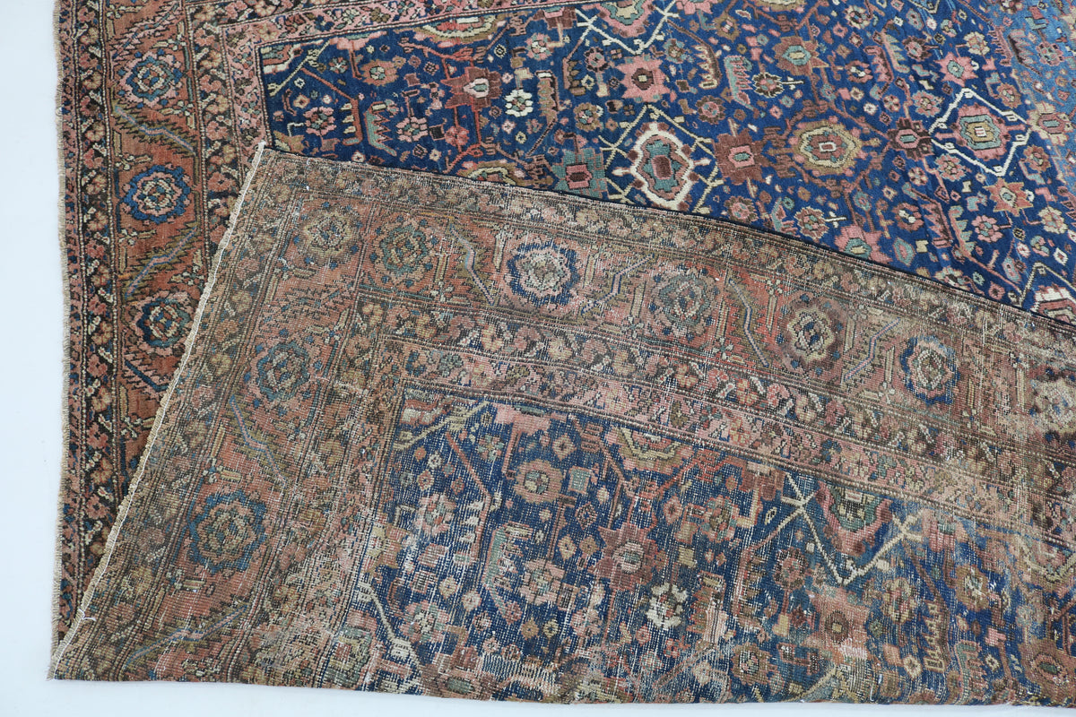 Folded antique Bakshayesh carpet showing detailed pattern and woven reverse side