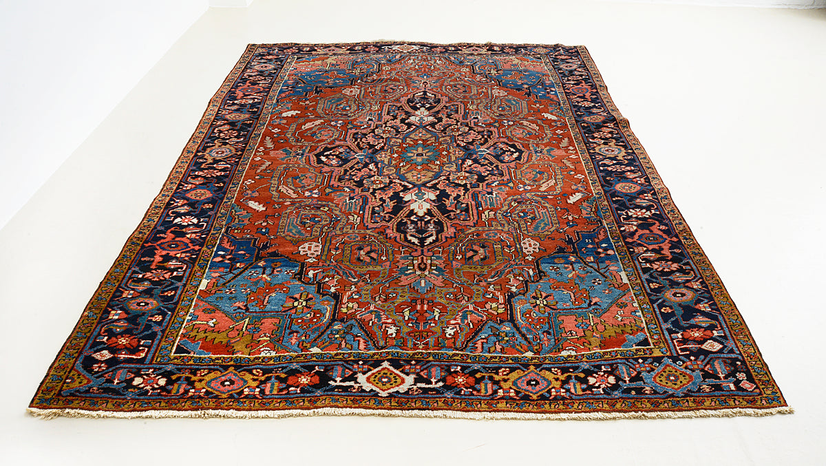 Full view of antique Heriz carpet with central medallion and warm terracotta field
