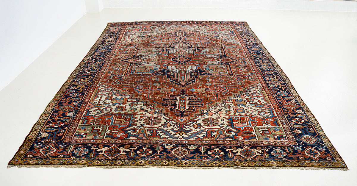 Full view of antique Heriz carpet with geometric medallion in terracotta, indigo and ivory