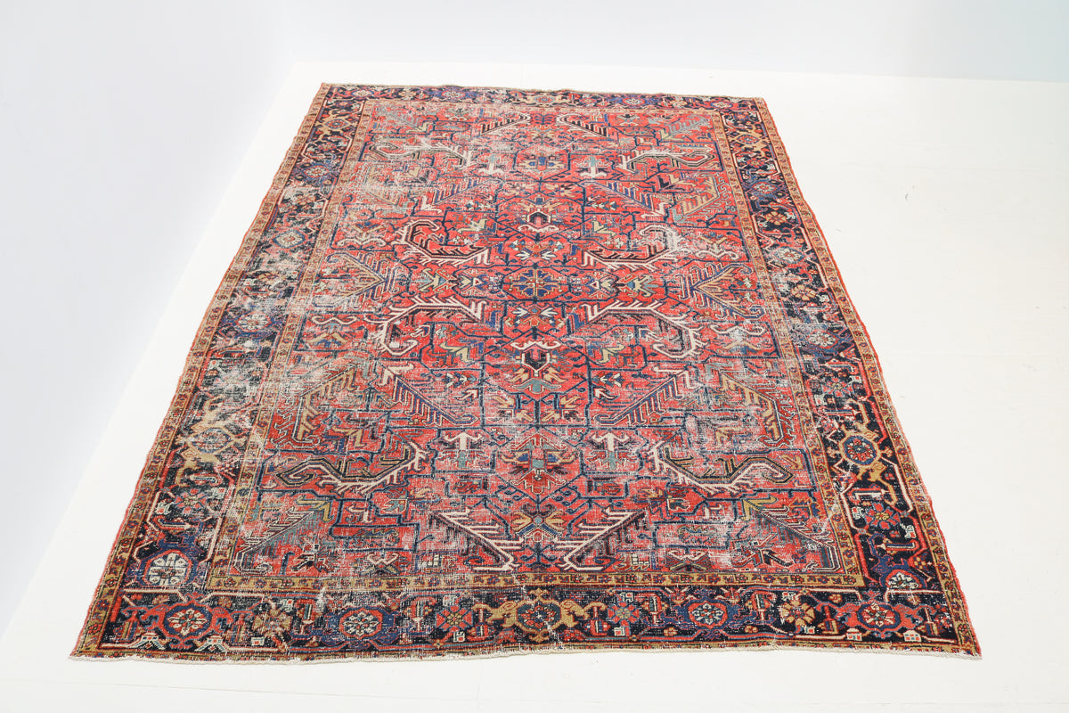 Full view of antique Persian Heriz rug featuring a large geometric medallion and rich terracotta tones
