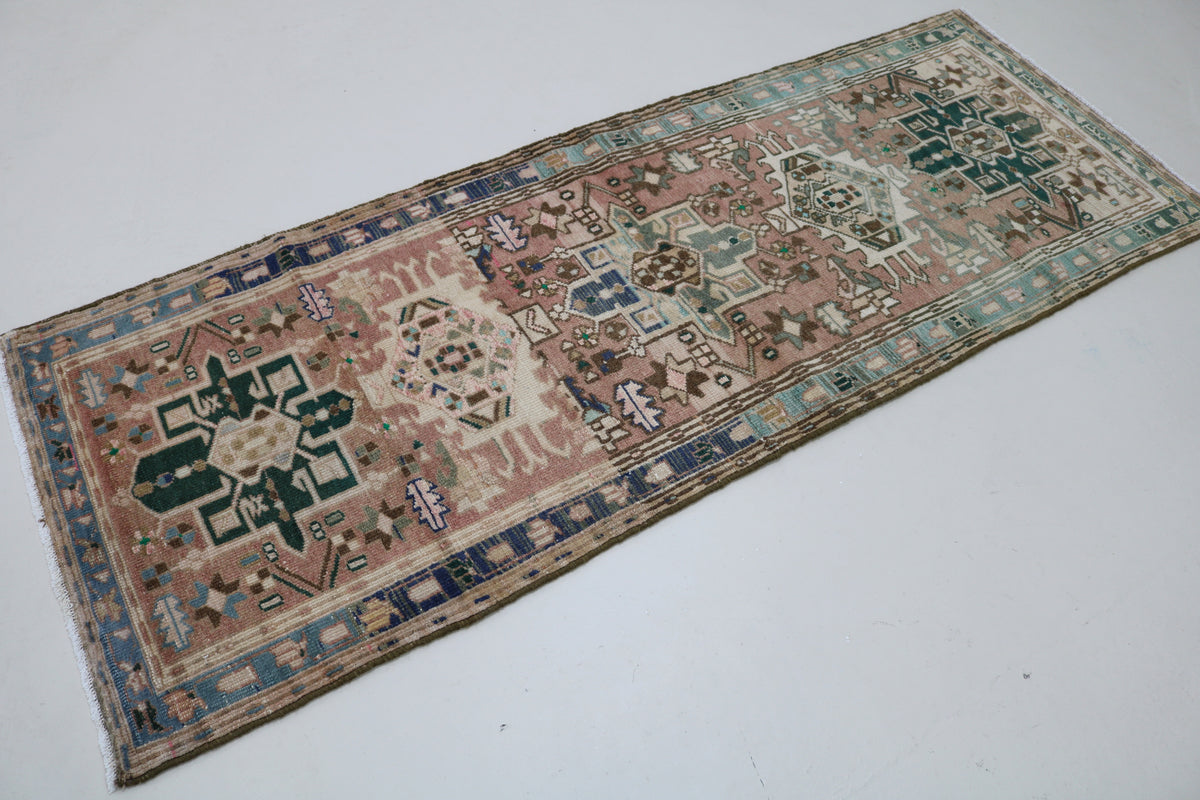 Angled view of Persian Heriz runner featuring muted pink, blue and beige tones