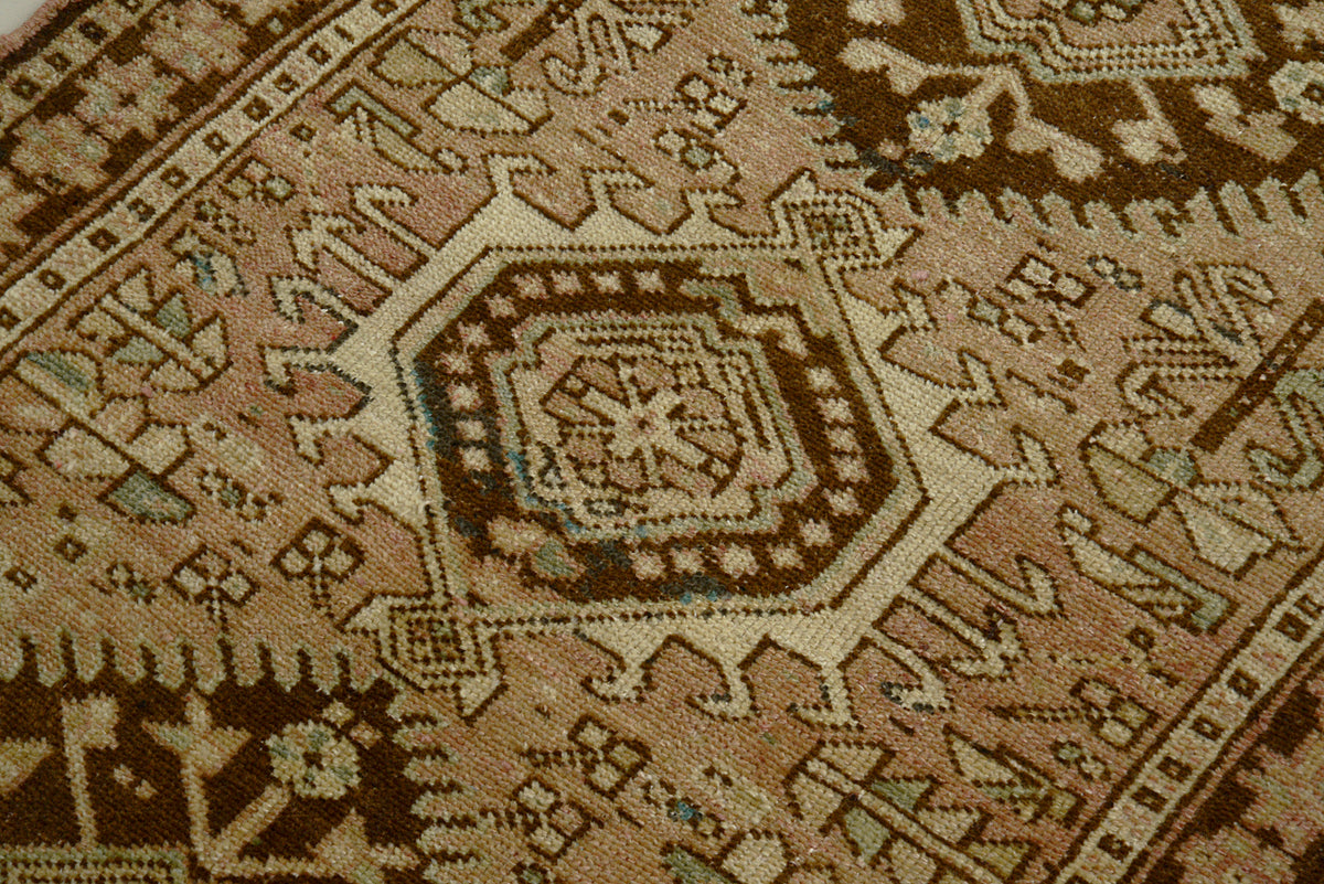 Close-up of antique Heriz runner showing geometric medallion in warm brown and beige tones